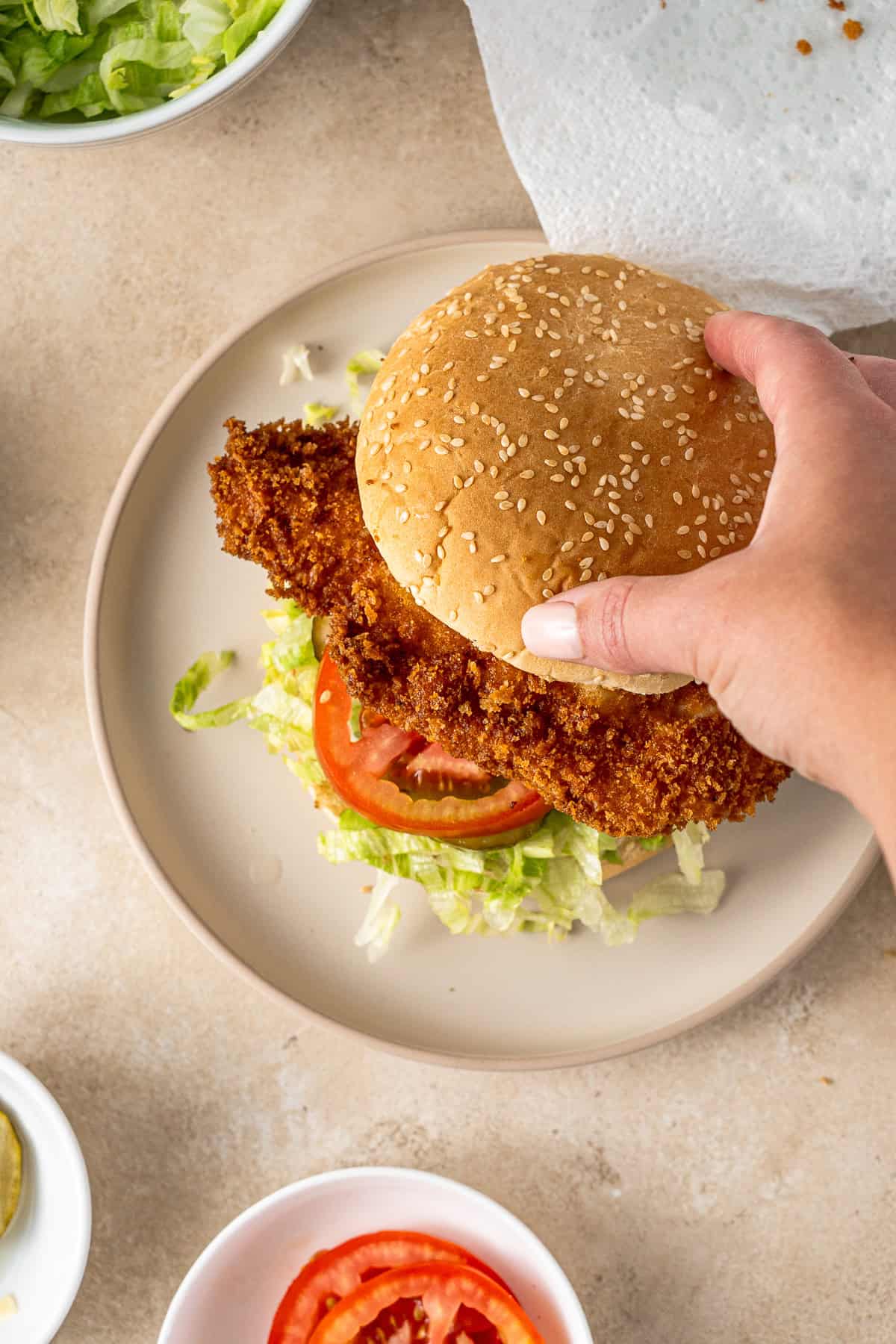 Placing the top bun on the burger.