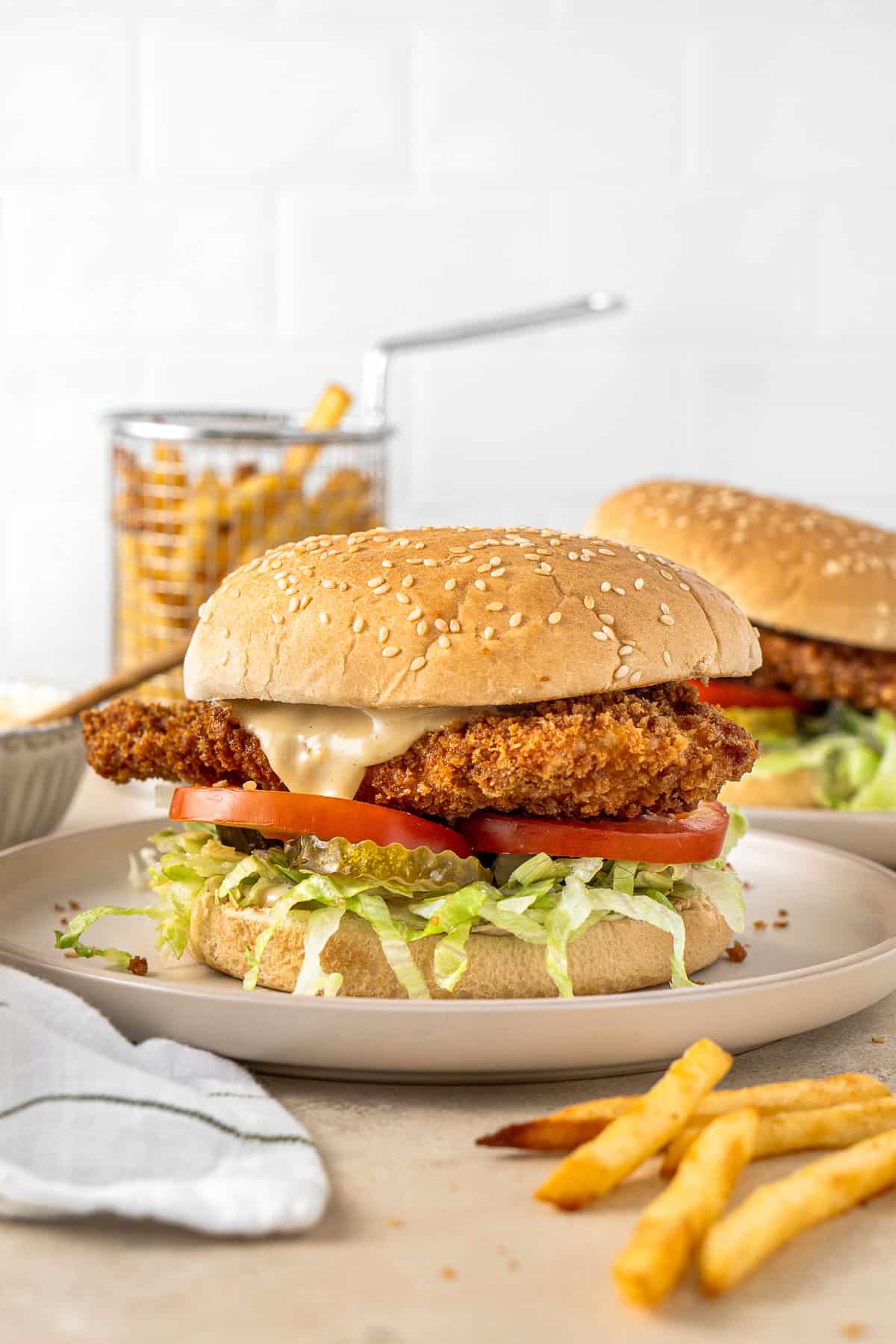 A chicken schnitzel burger with honey mustard sauce and tomato, pickles and lettuce.