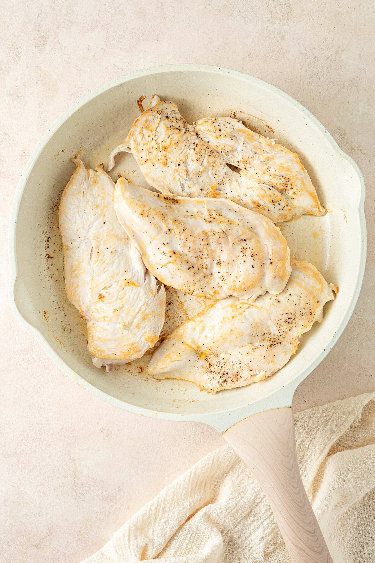 Searing the chicken breast in a frying pan.