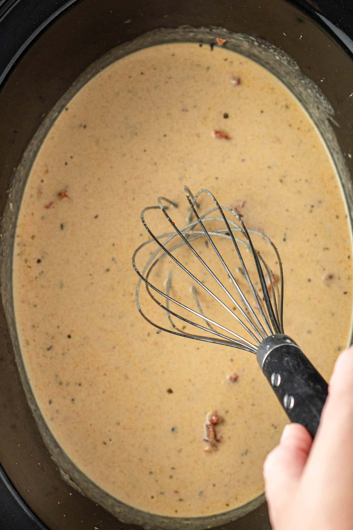Whisking the creamy sauce in the slow cooker.