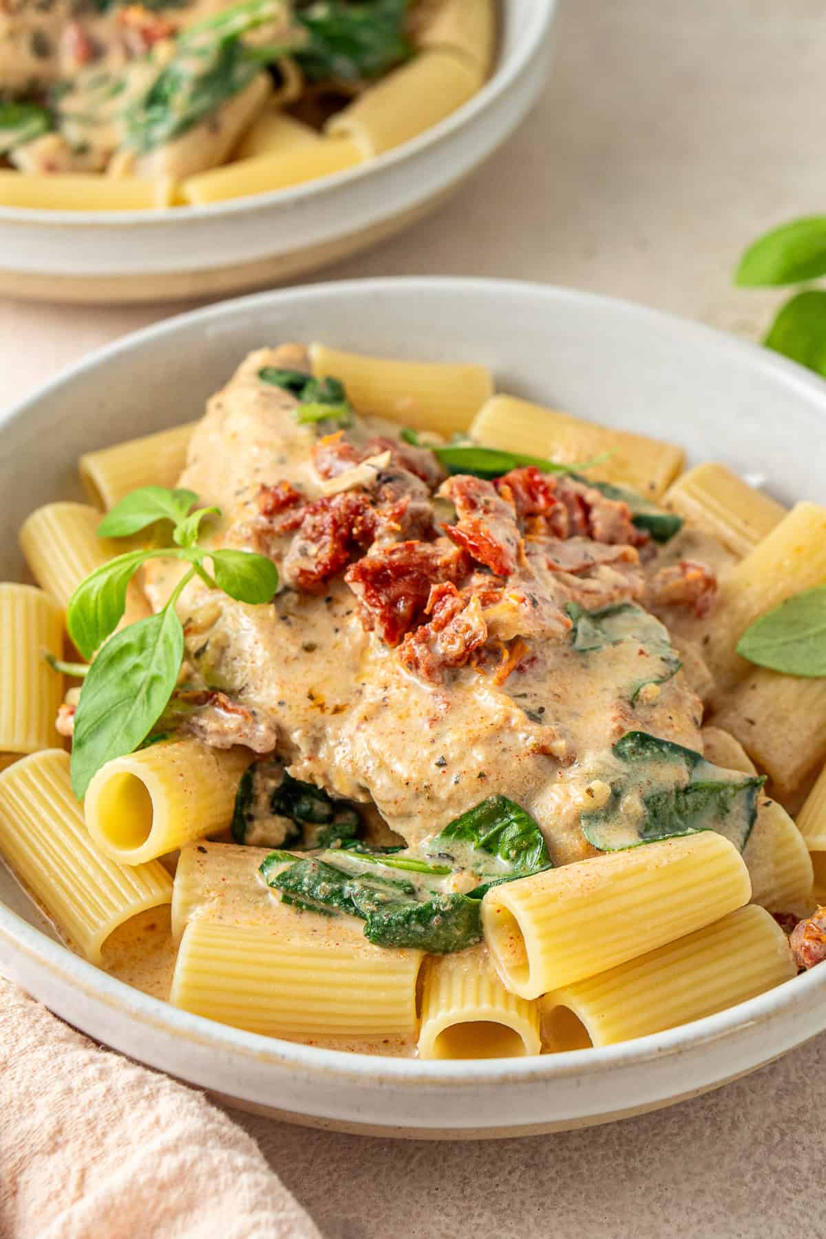 The chicken breast served over pasta with lots of sauce.