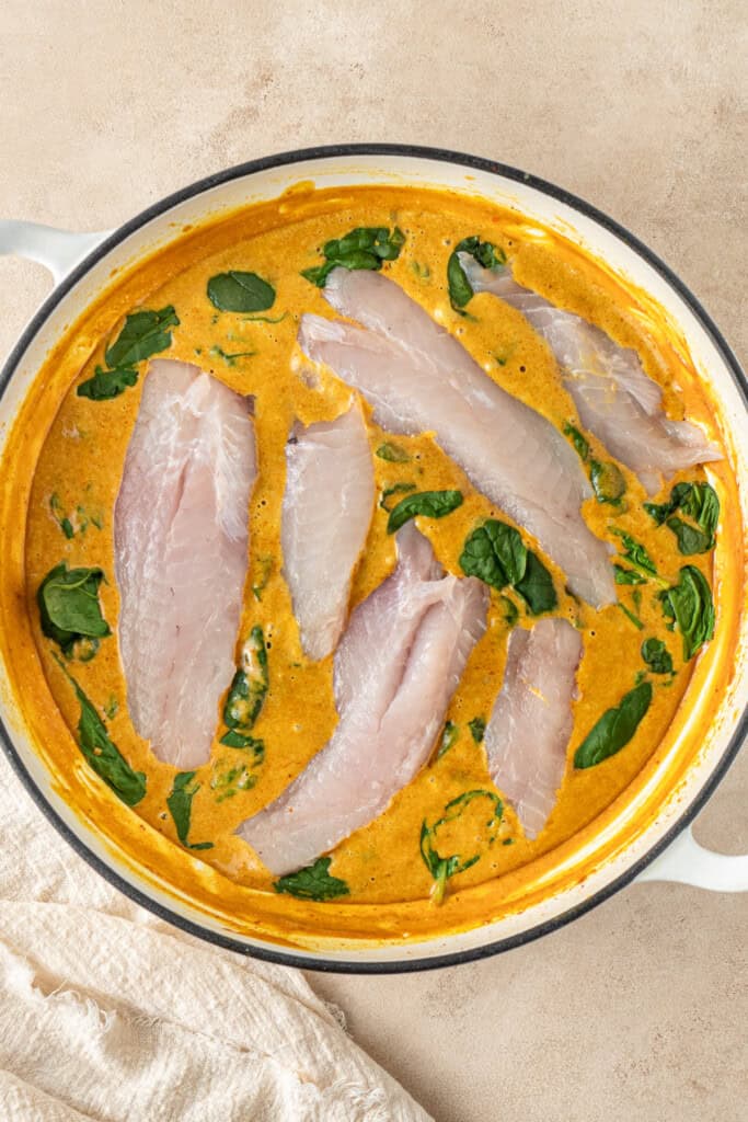 Adding the spinach and fish to the curry sauce.