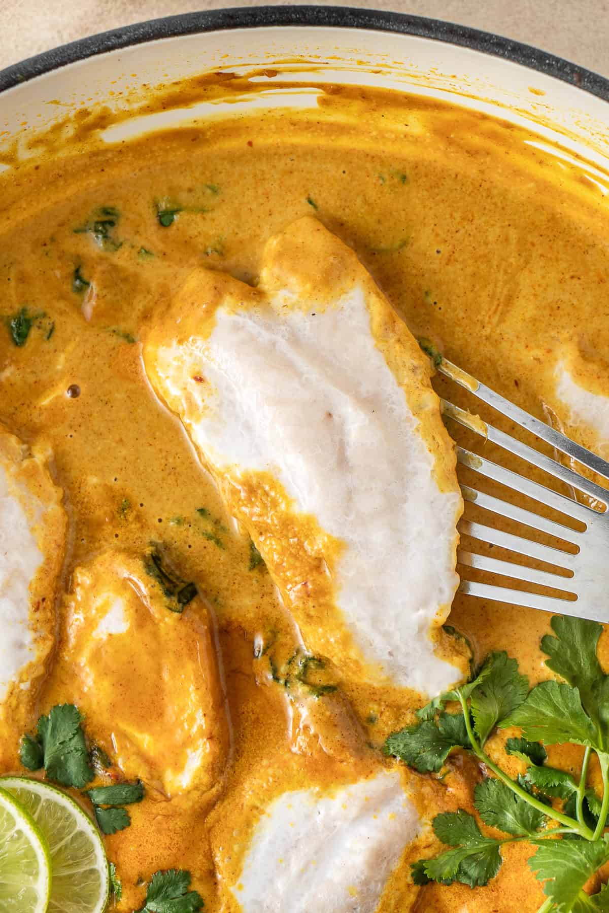 Scooping out a piece of poached fish from the curry.