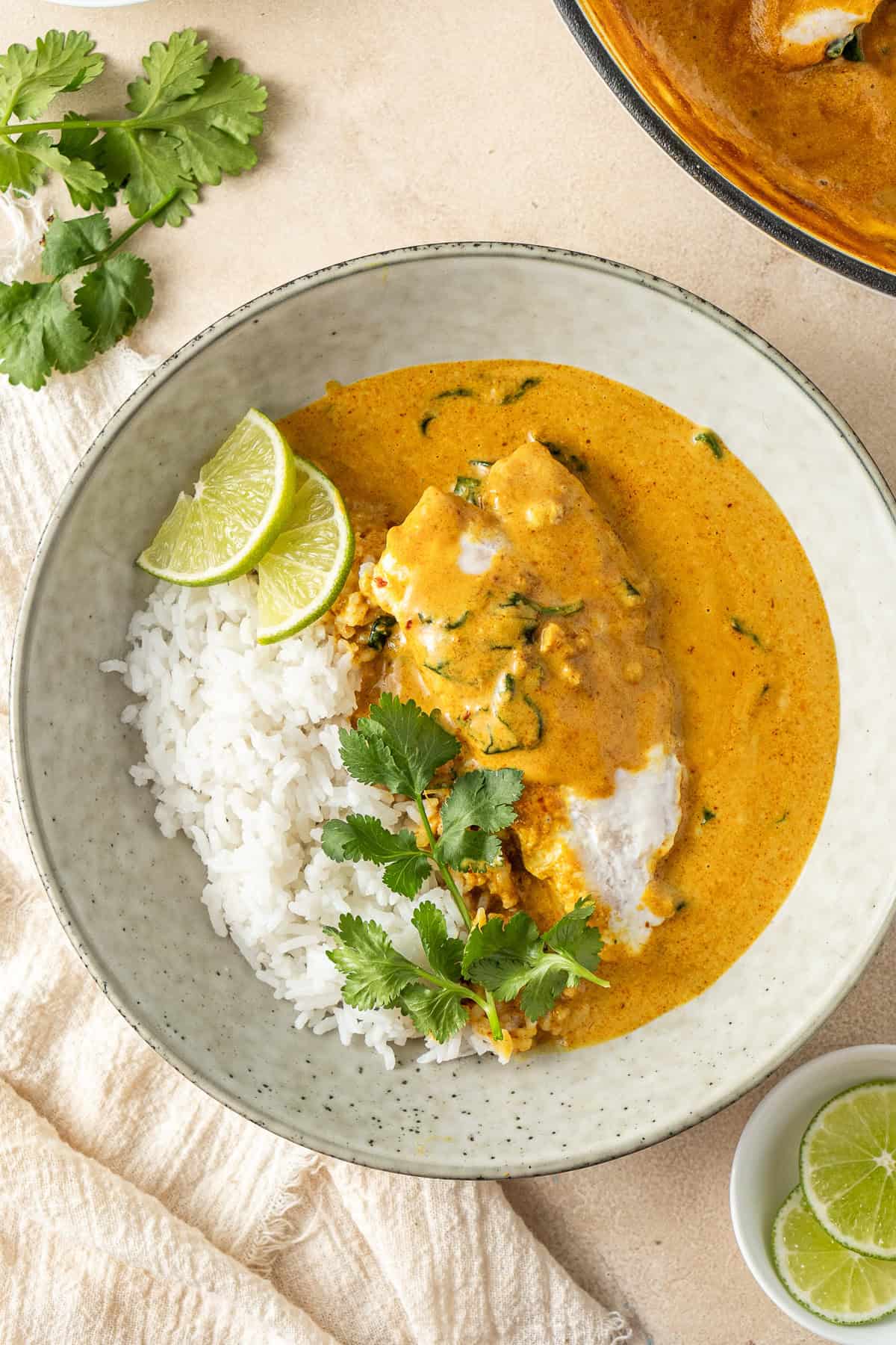 Yellow fish curry served in a bowl of rice with coriander and lime.