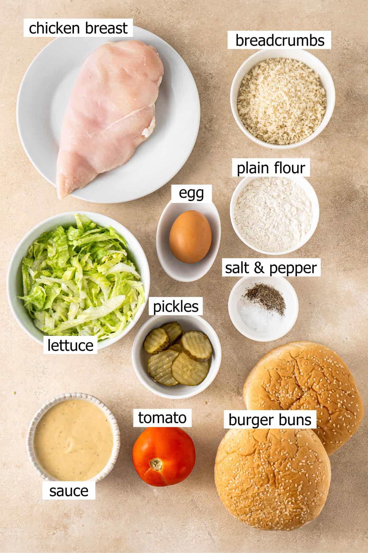 All ingredients needed to make a chicken schnitzel burger laid out in bowls.