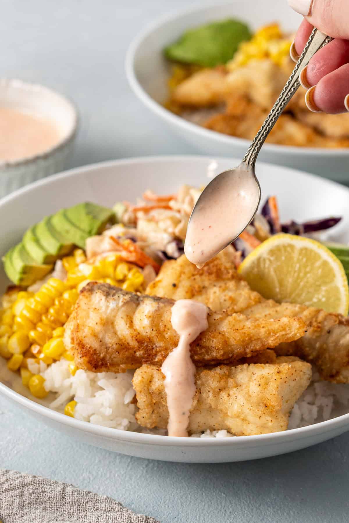 Drizzling the sauce over the fried fish bowls. 