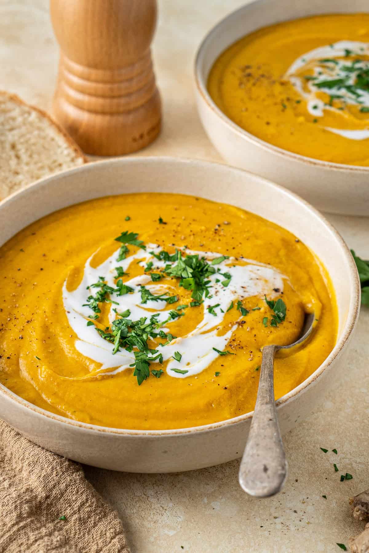 A spoon in a brown bowl of lentil and carrot soup.