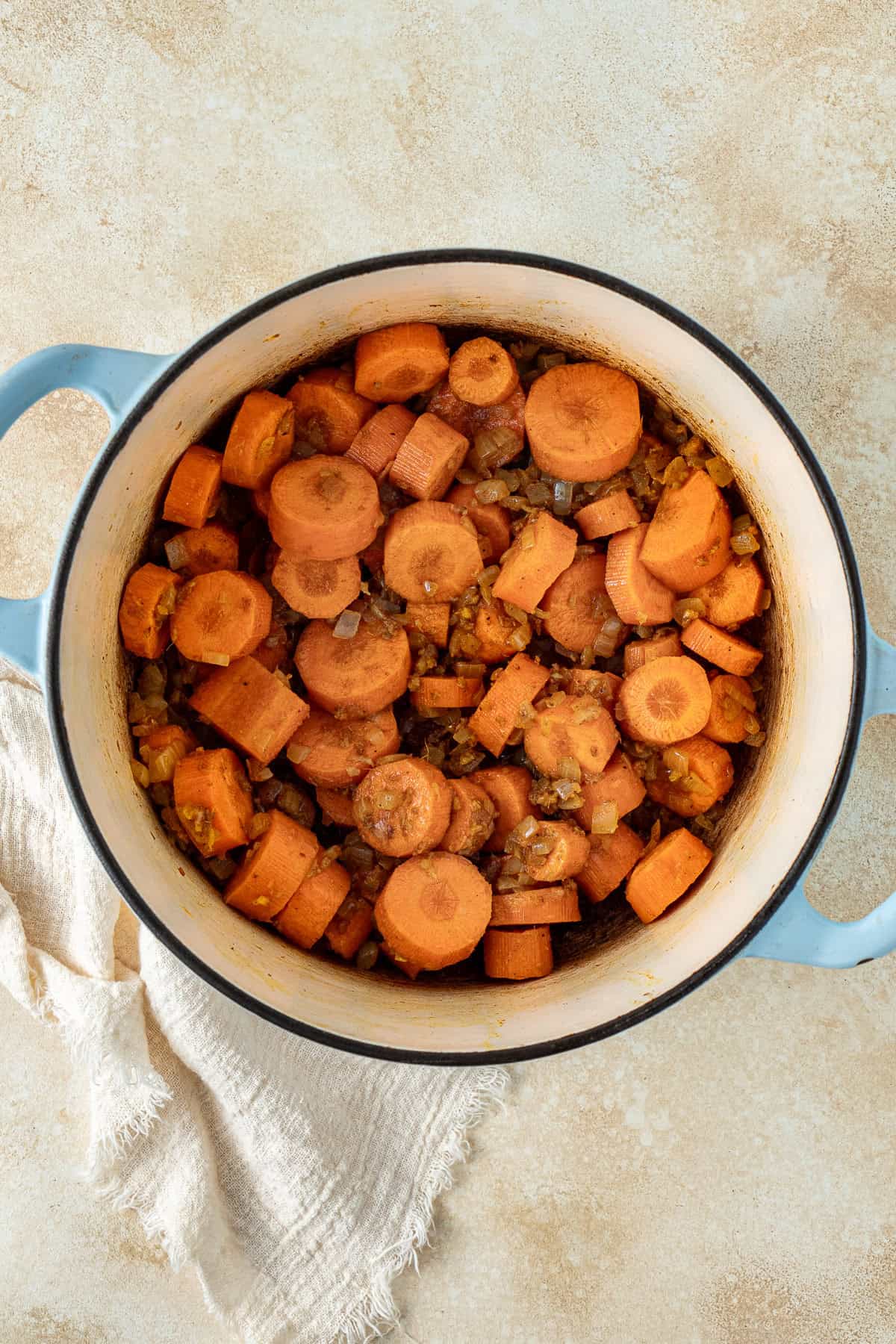 The spices and carrots added to the onions in the pot.