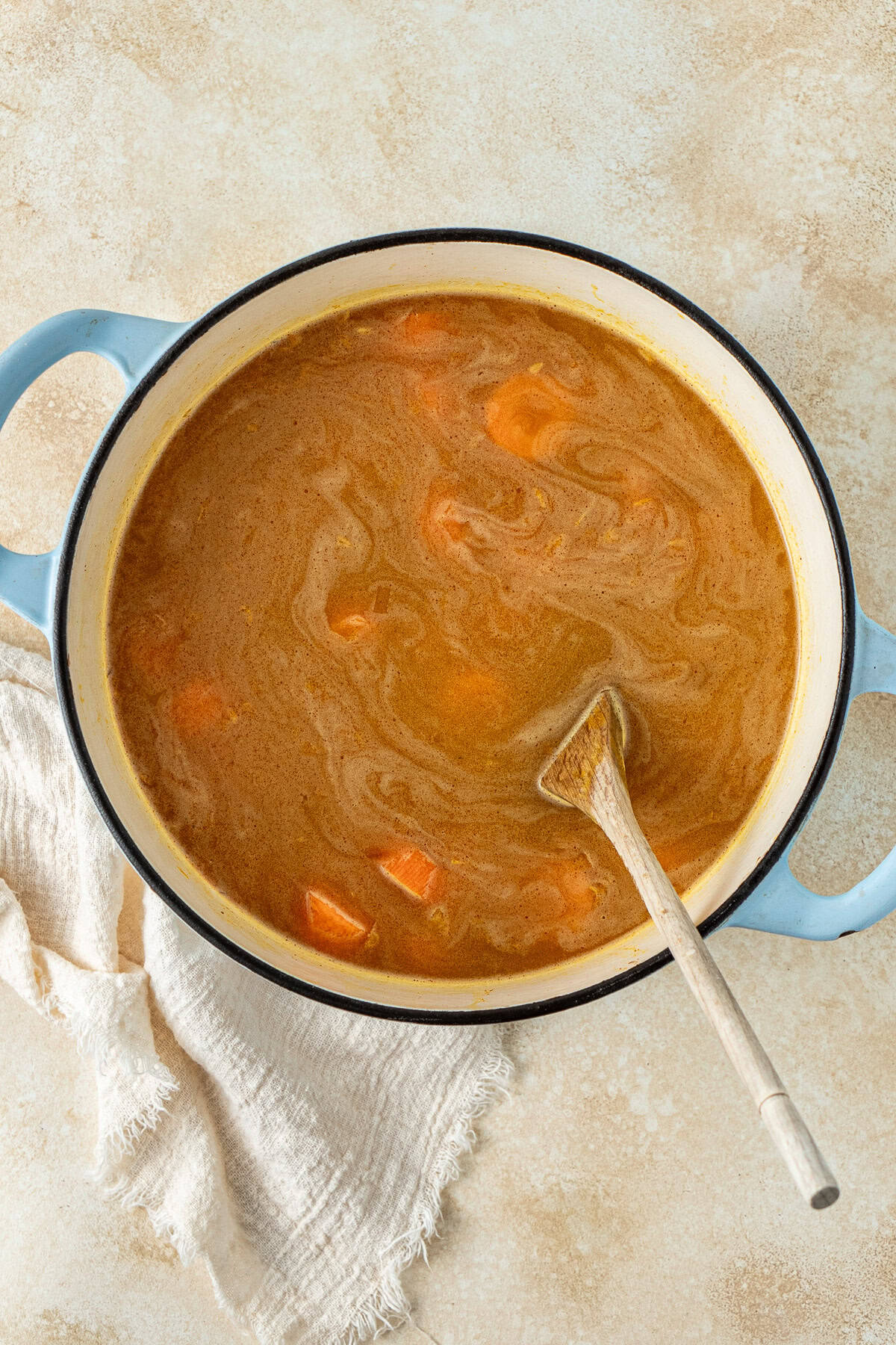 The liquid and lentils added to the pot with a wooden spoon.