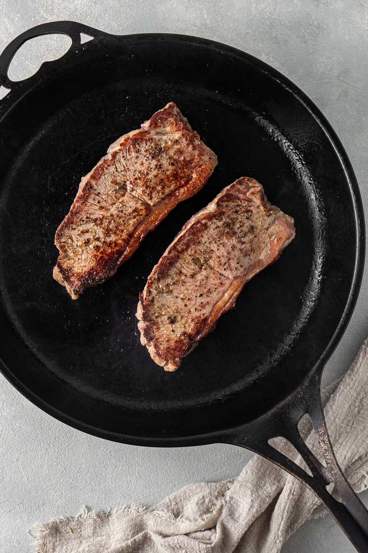 The steak cooking in a cast iron pan.