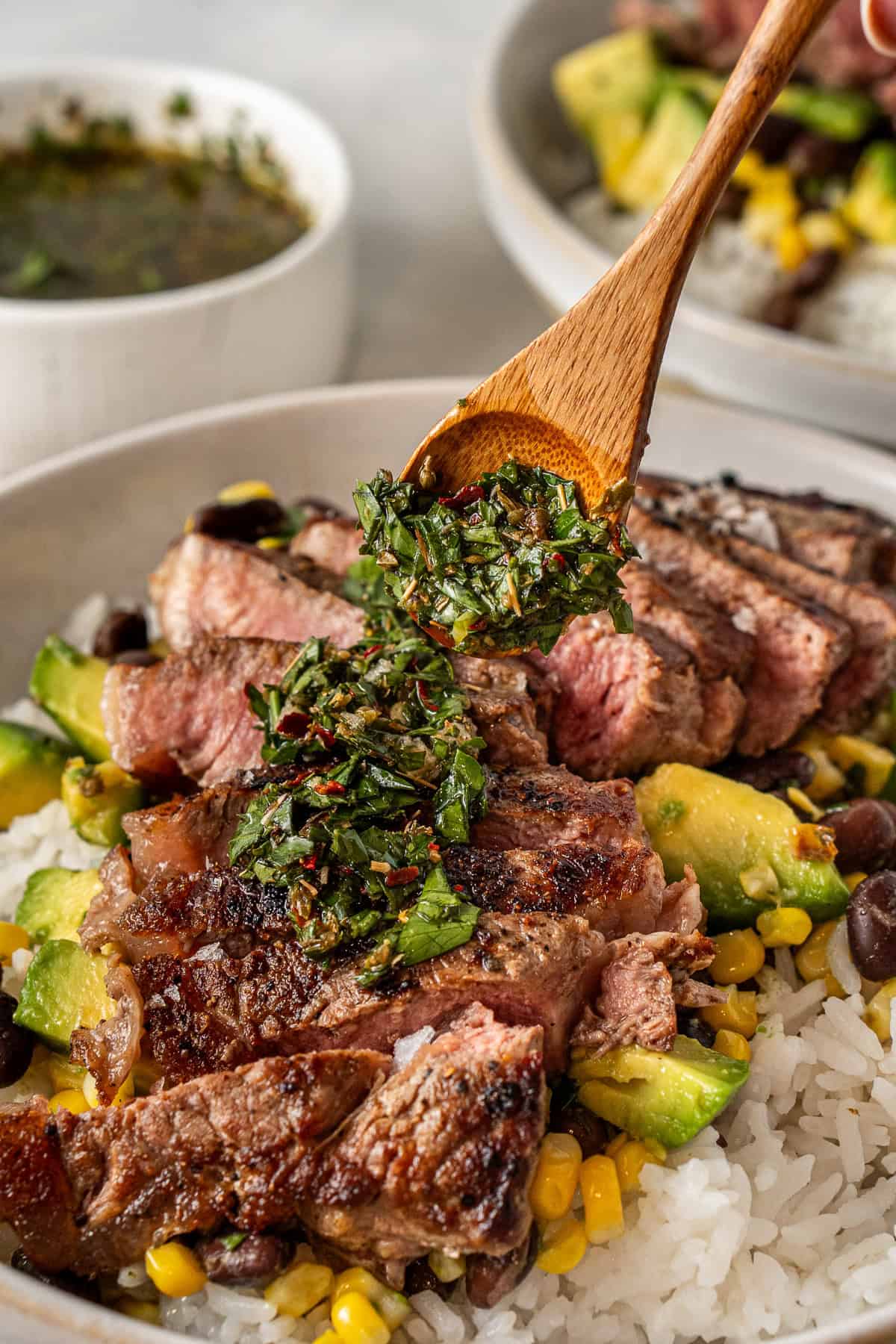 Spooning the chimichurri over the sliced steak.
