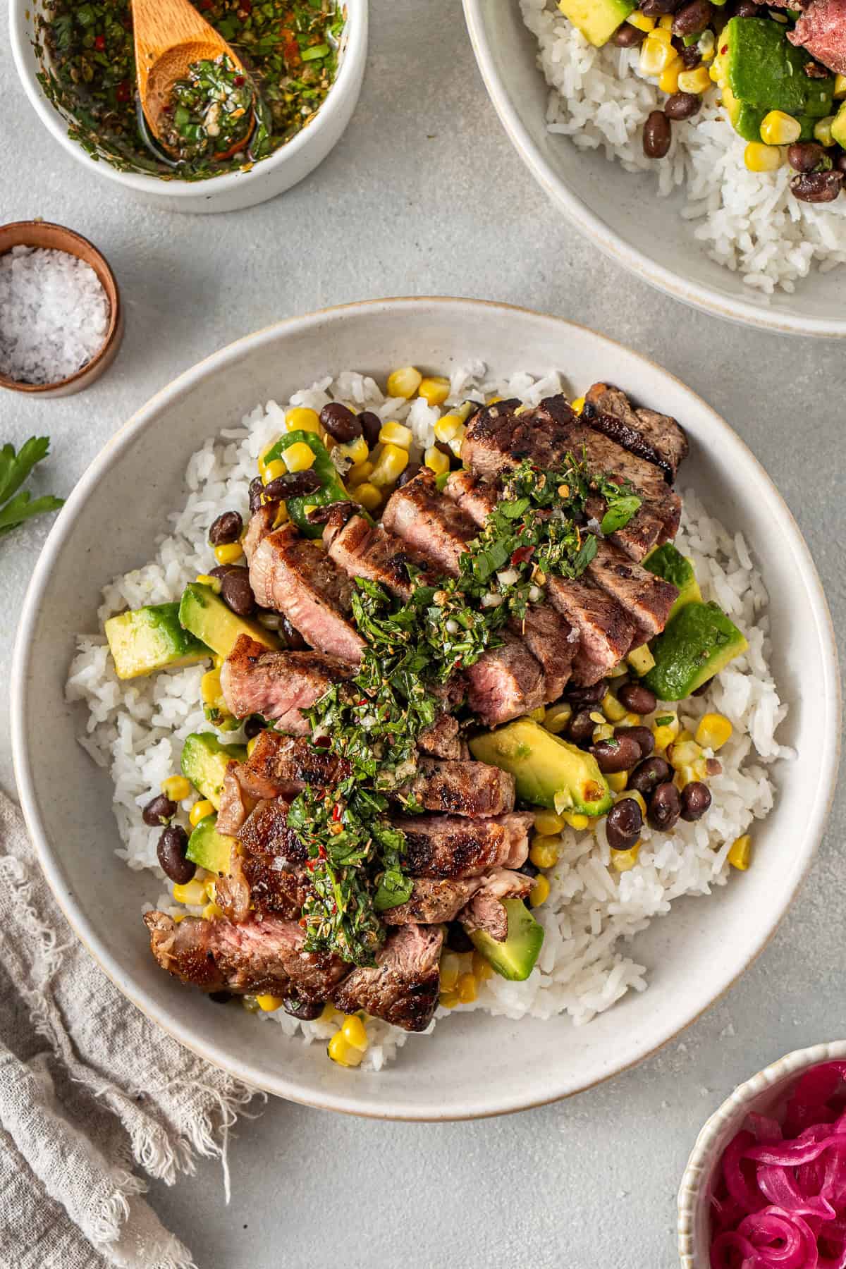 Steak rice bowl with chimichurri on a grey background. 