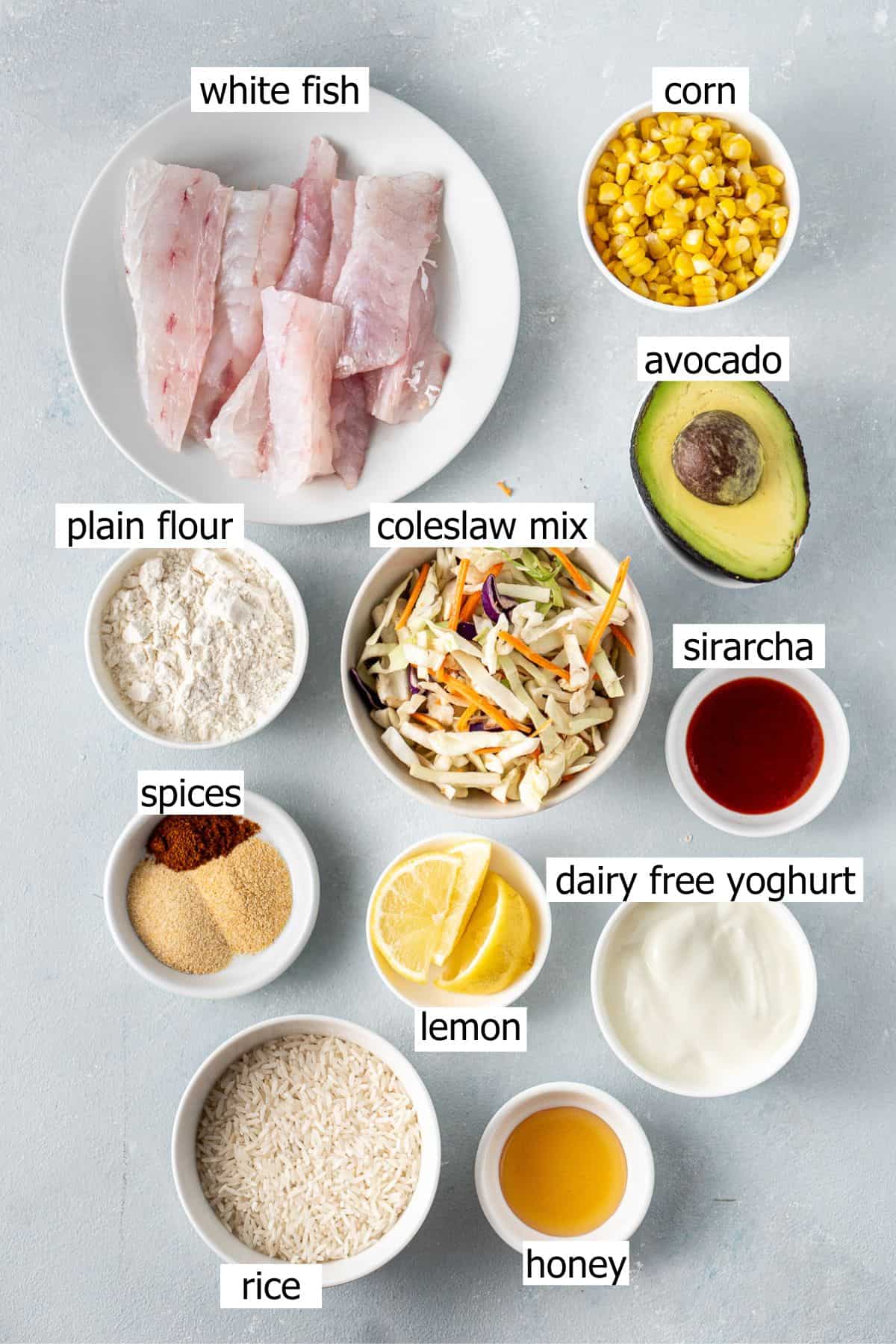 All ingredients needed to make fish taco bowls laid out in small bowls on a blue background.