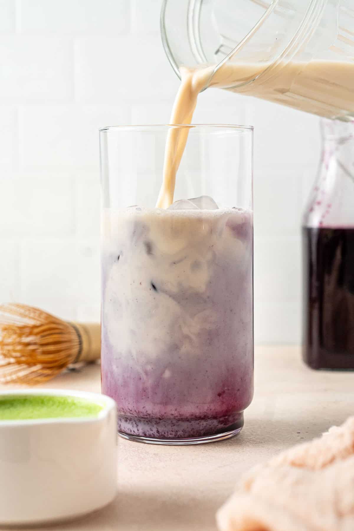 Pouring in the oat milk to the glass.