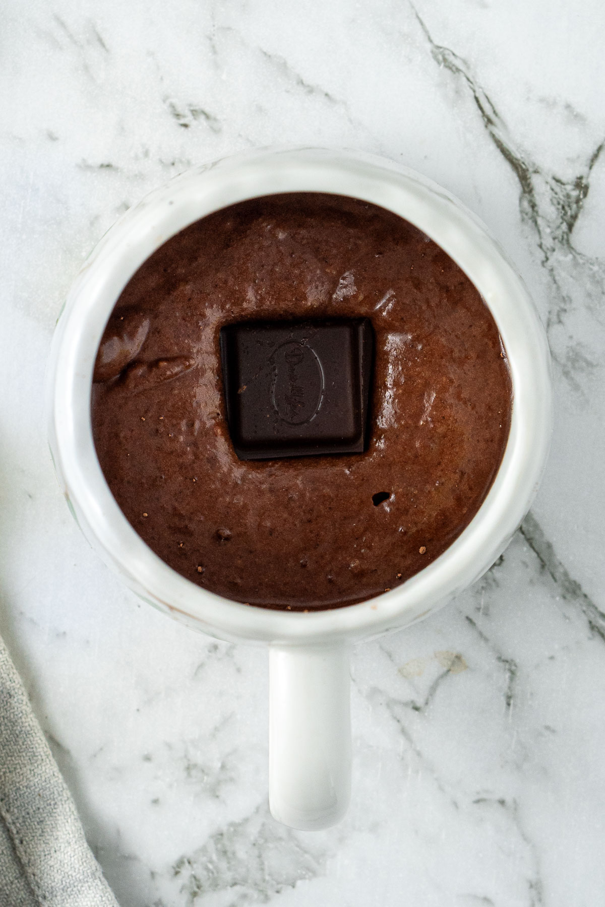 The mug cake batter with a square of dark chocolate in the centre.