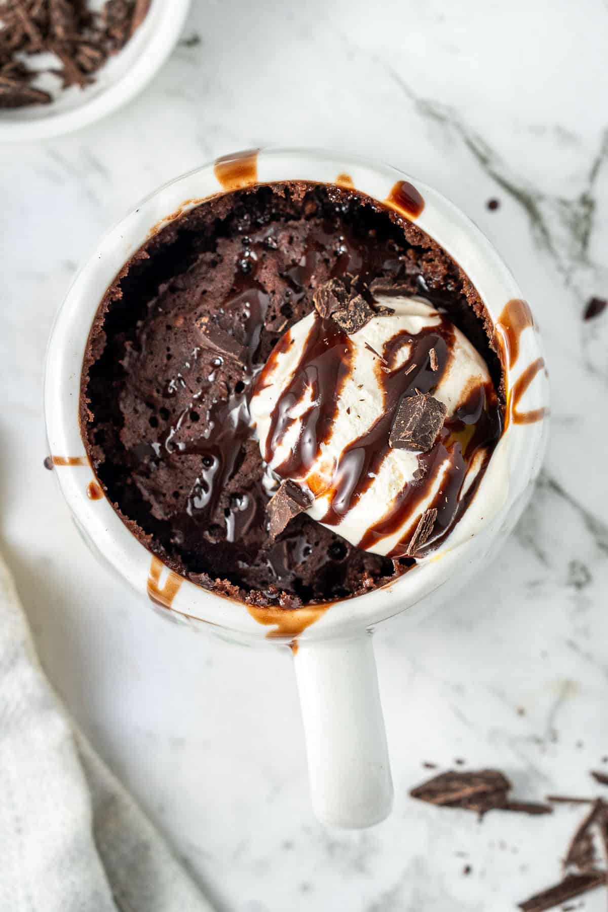 The cooked chocolate mug cake with ice cream and chocolate syrup.