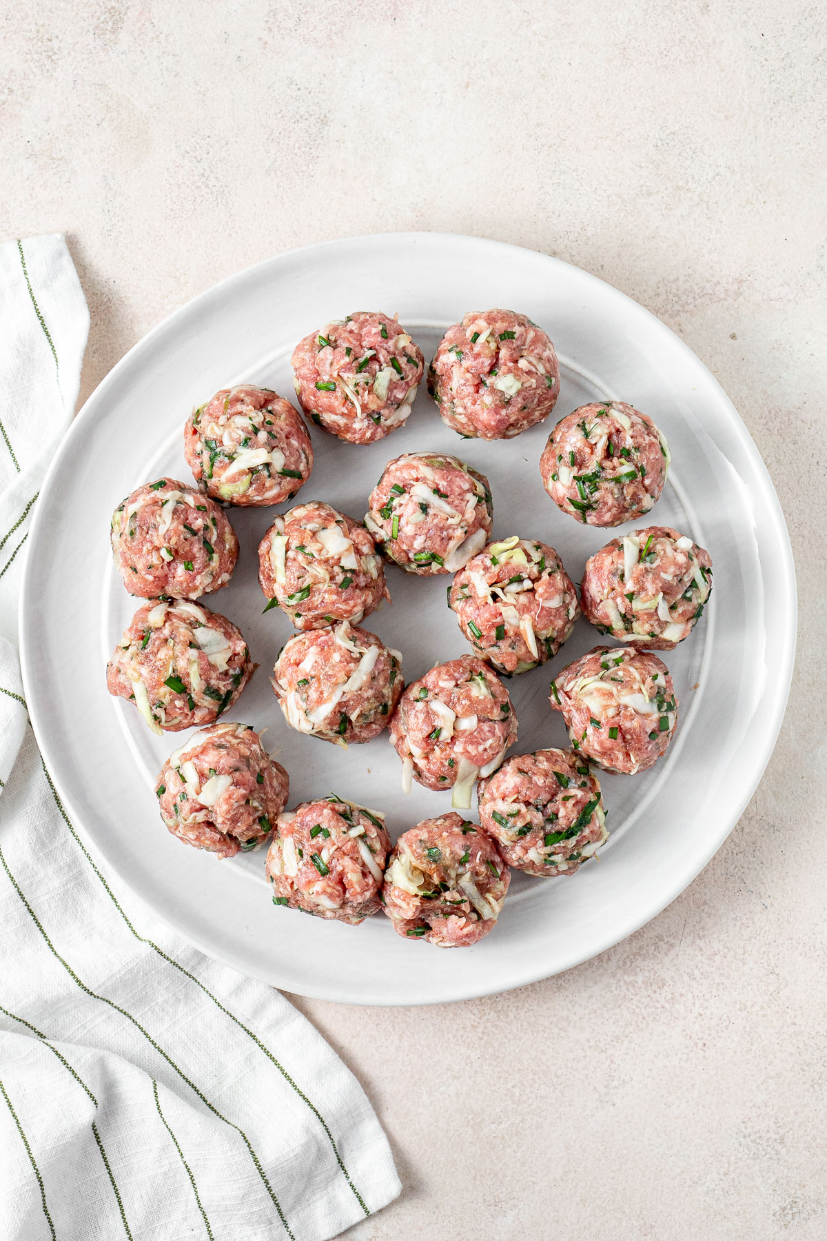 Balls of filling mixture laid out on a white plate.
