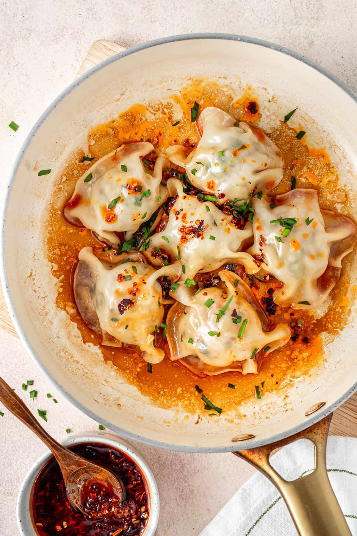 No fold pork dumplins in a frying pan with chilli oil.