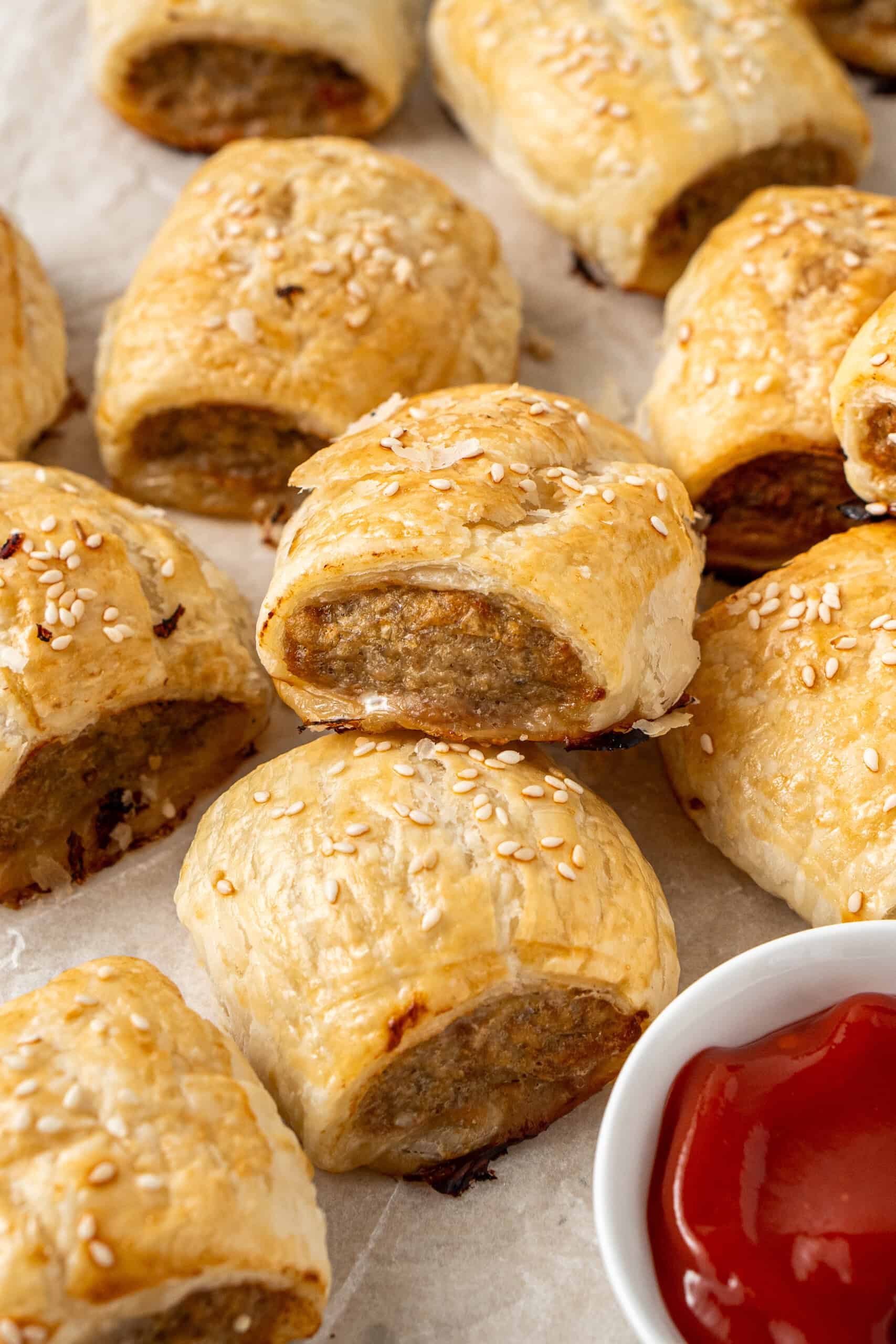 Close up of a pork and apple sausage roll being served with tomato sauce.