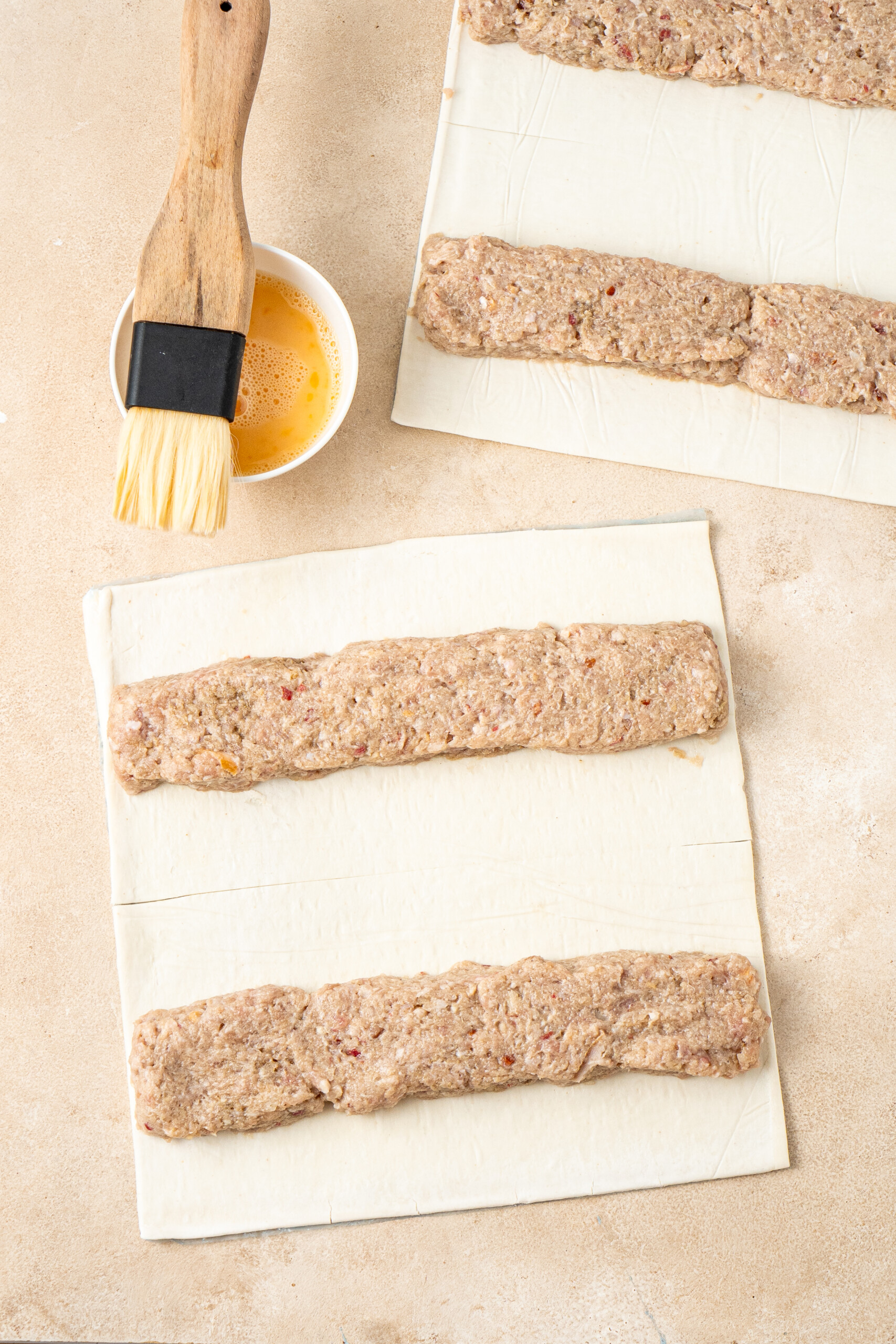 The pork filling shaped into logs on sheets of puff pastry.