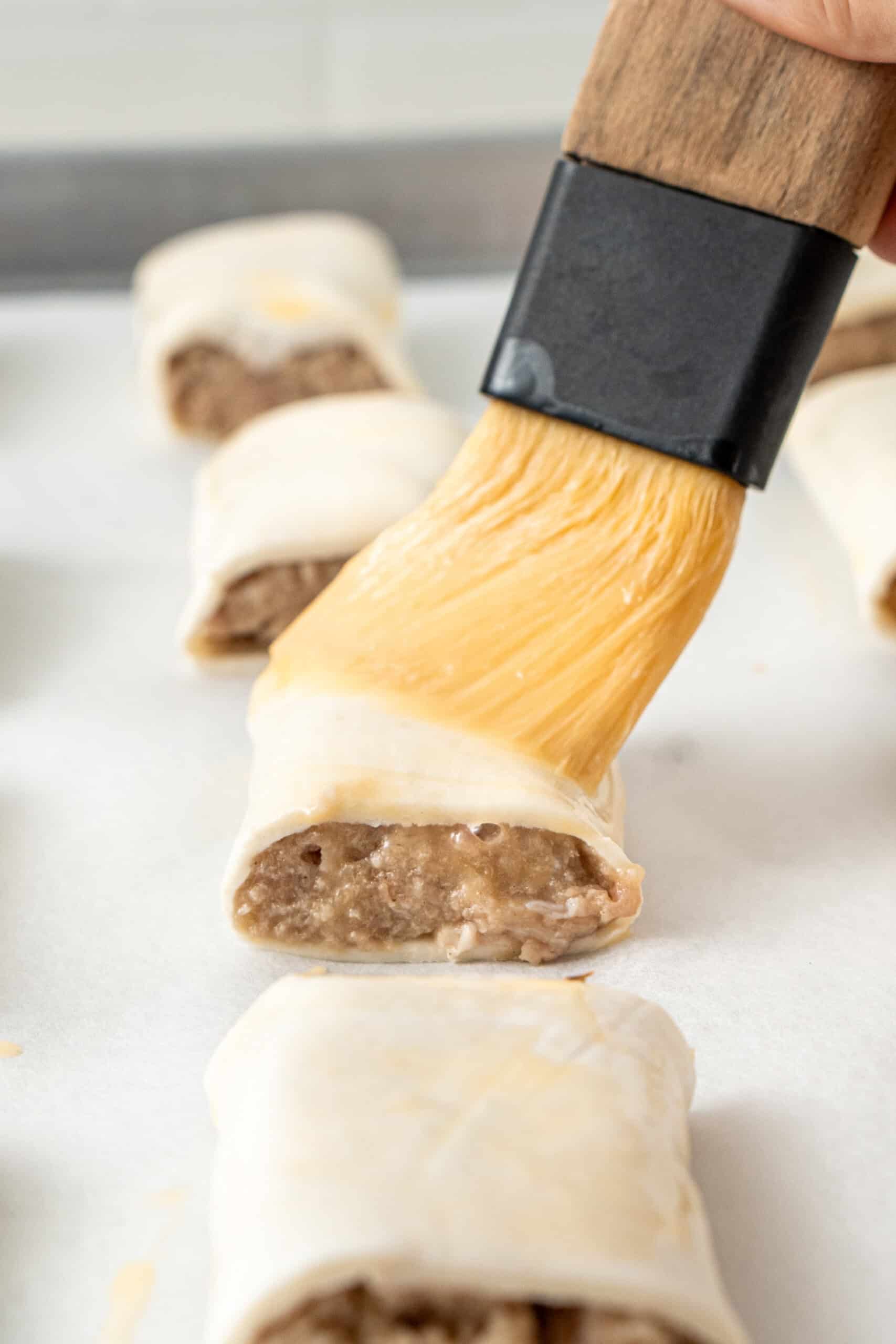 Brushing the sausage rolls with egg wash.