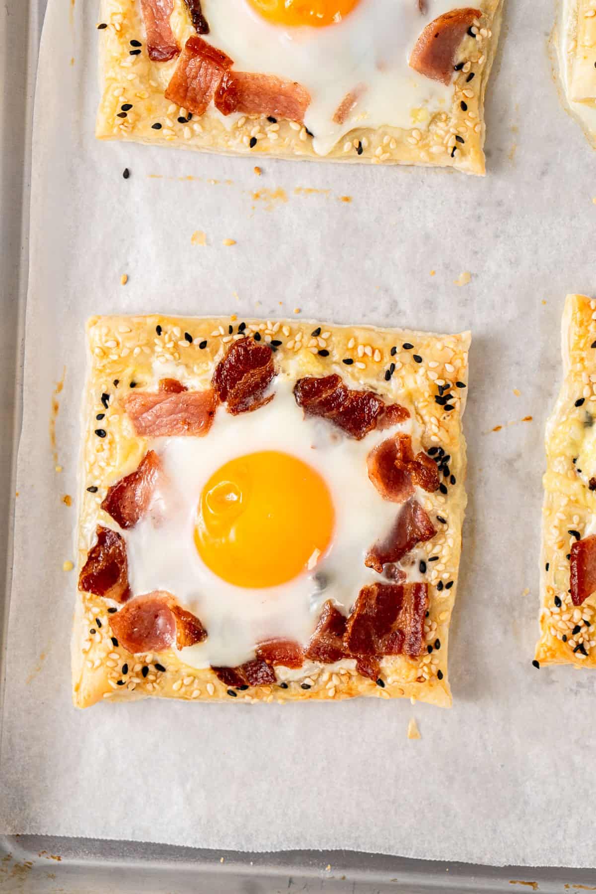 The baked breakfast pastries with the egg cooked on a baking tray.