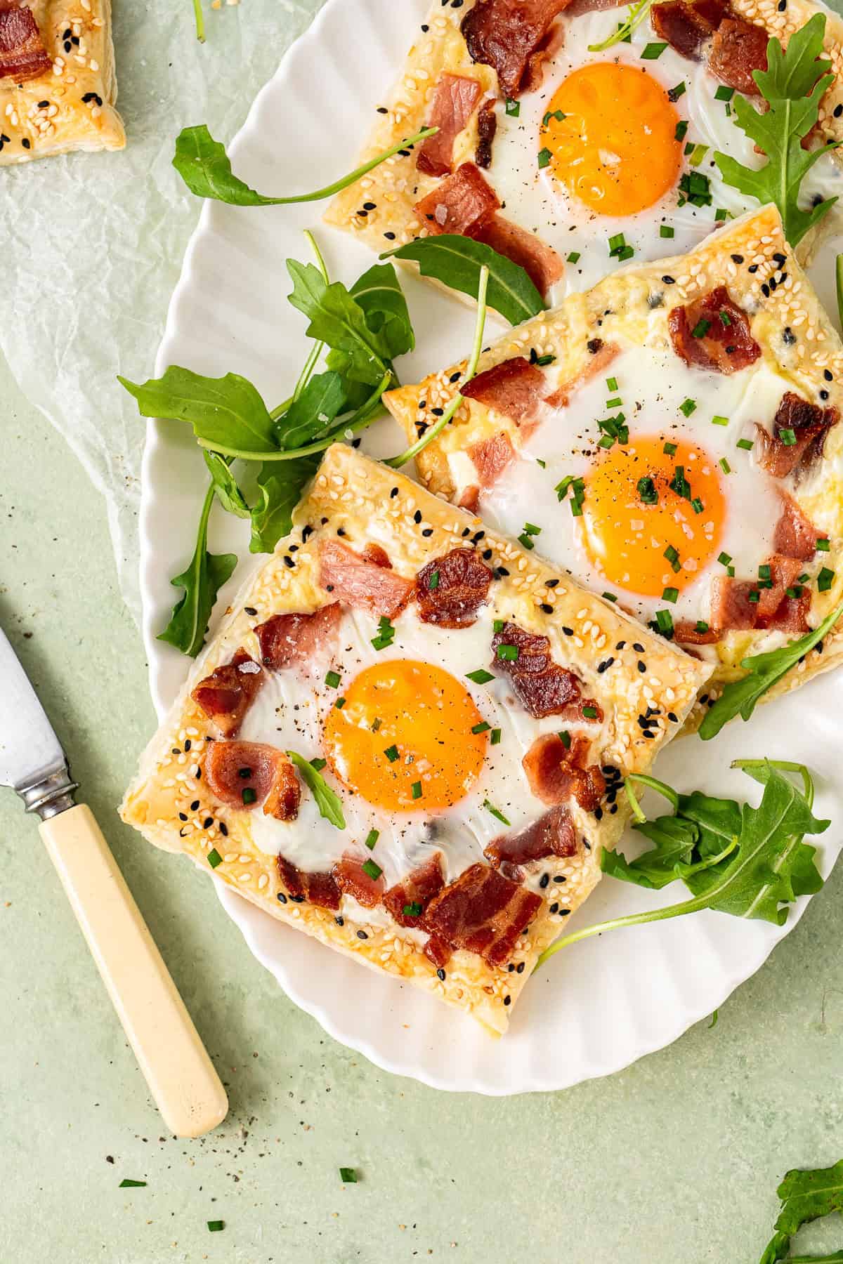 Puff pastry breakfast tarts on a white plate with rocket leaves.