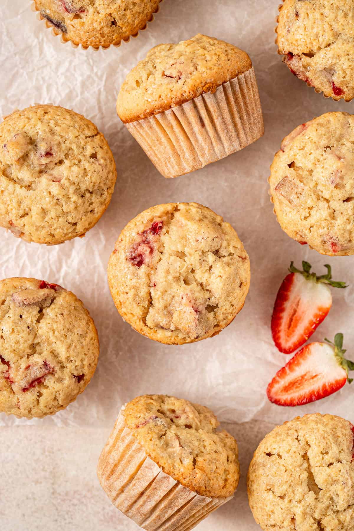 Strawberry rhubarb muffins laid out with a fresh strawberry.