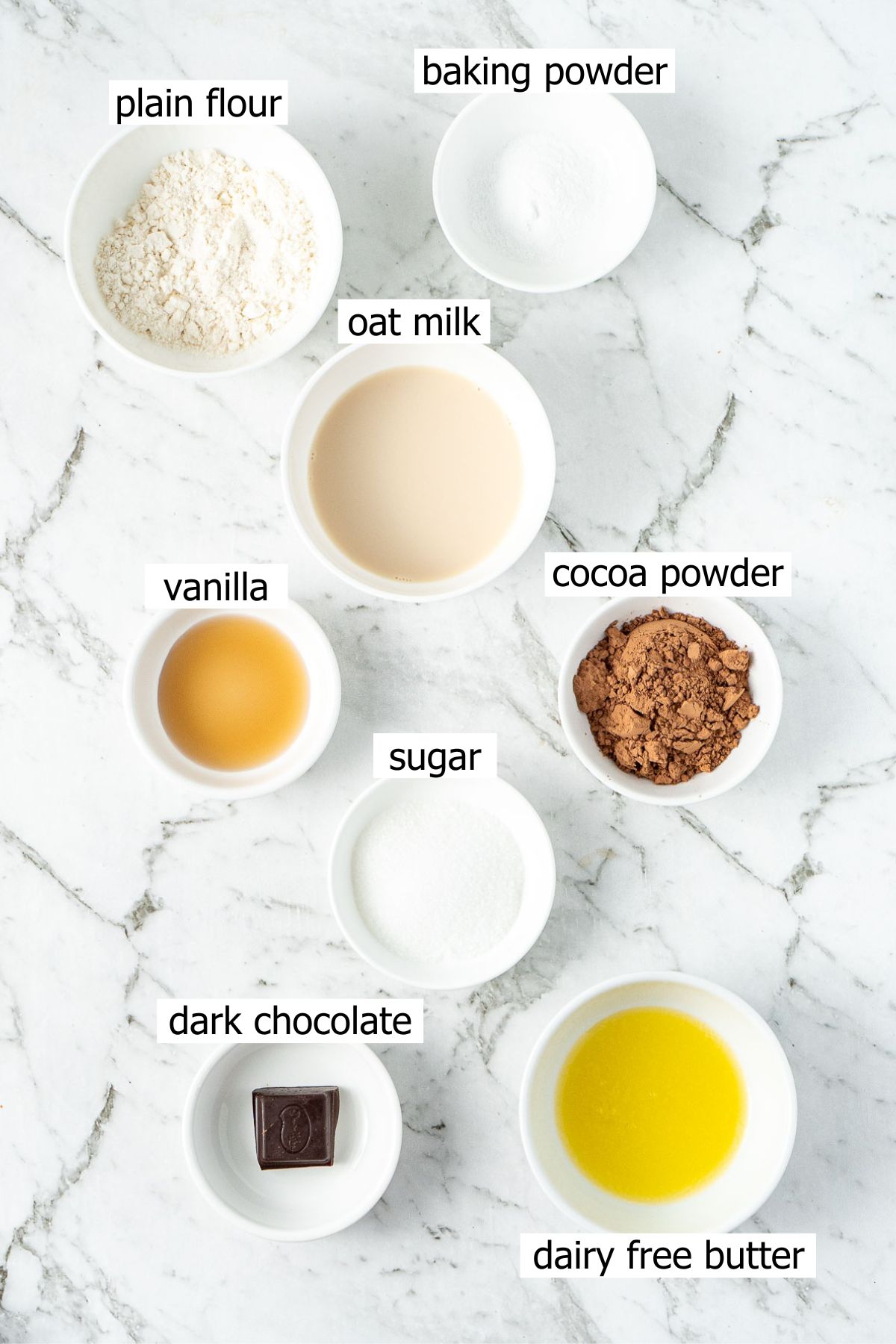 All ingredients needed to make a vegan chocolate mug cake laid out in bowls.