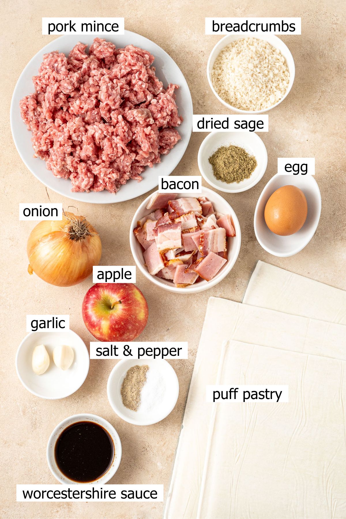 All ingredients needed to make pork and apple sausage rolls laid out in bowls.
