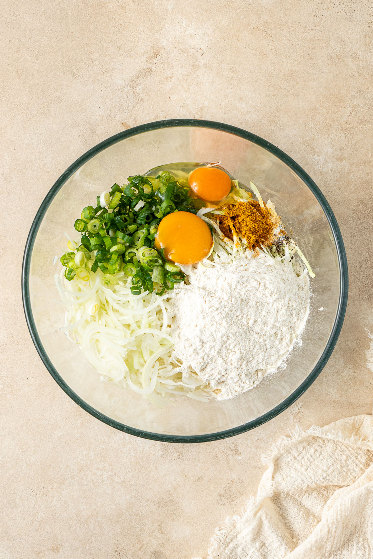 All ingredients for the cabbage fritters in a glass mixing bowl.
