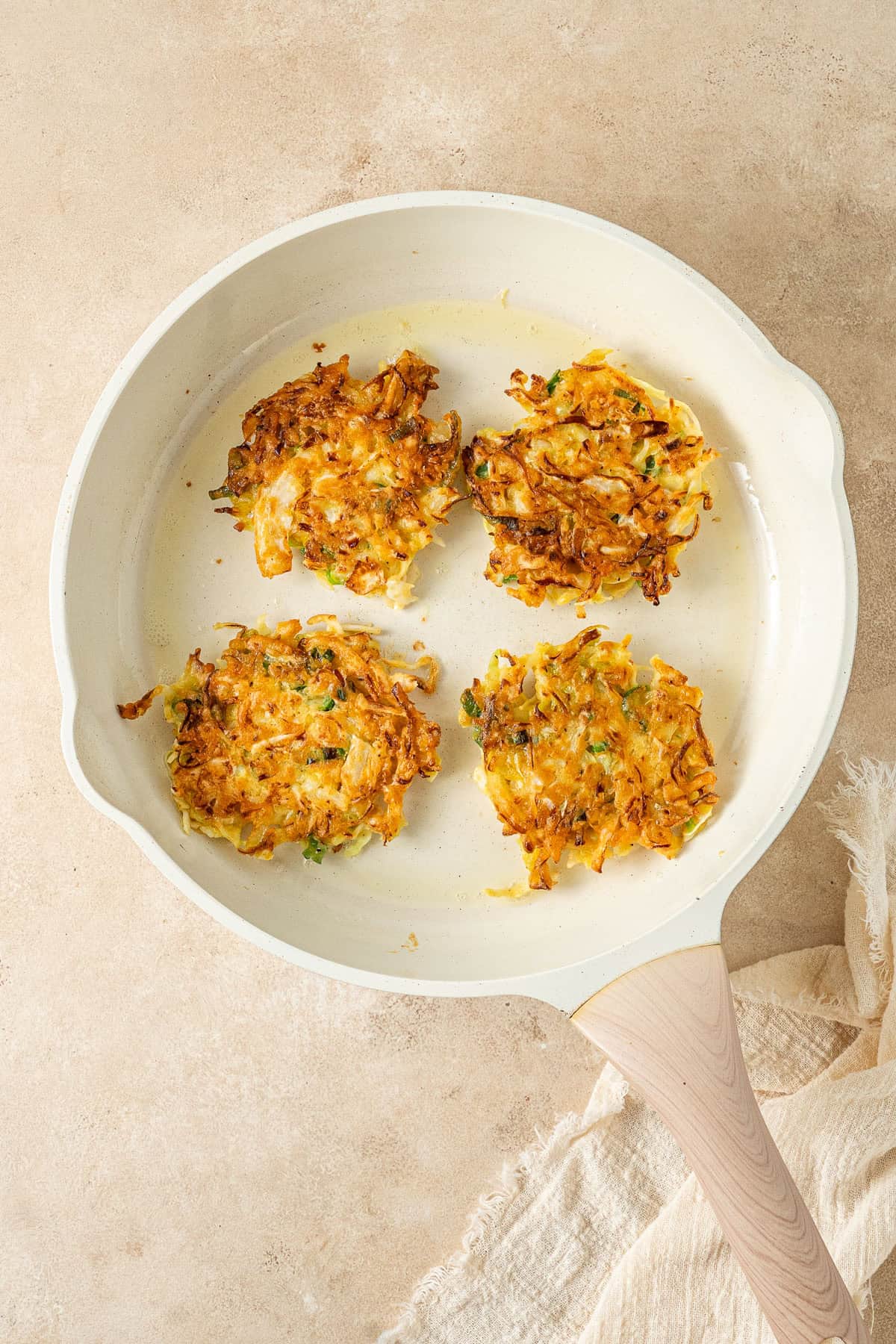 The cooked fritters in a frying pan, golden and crispy.
