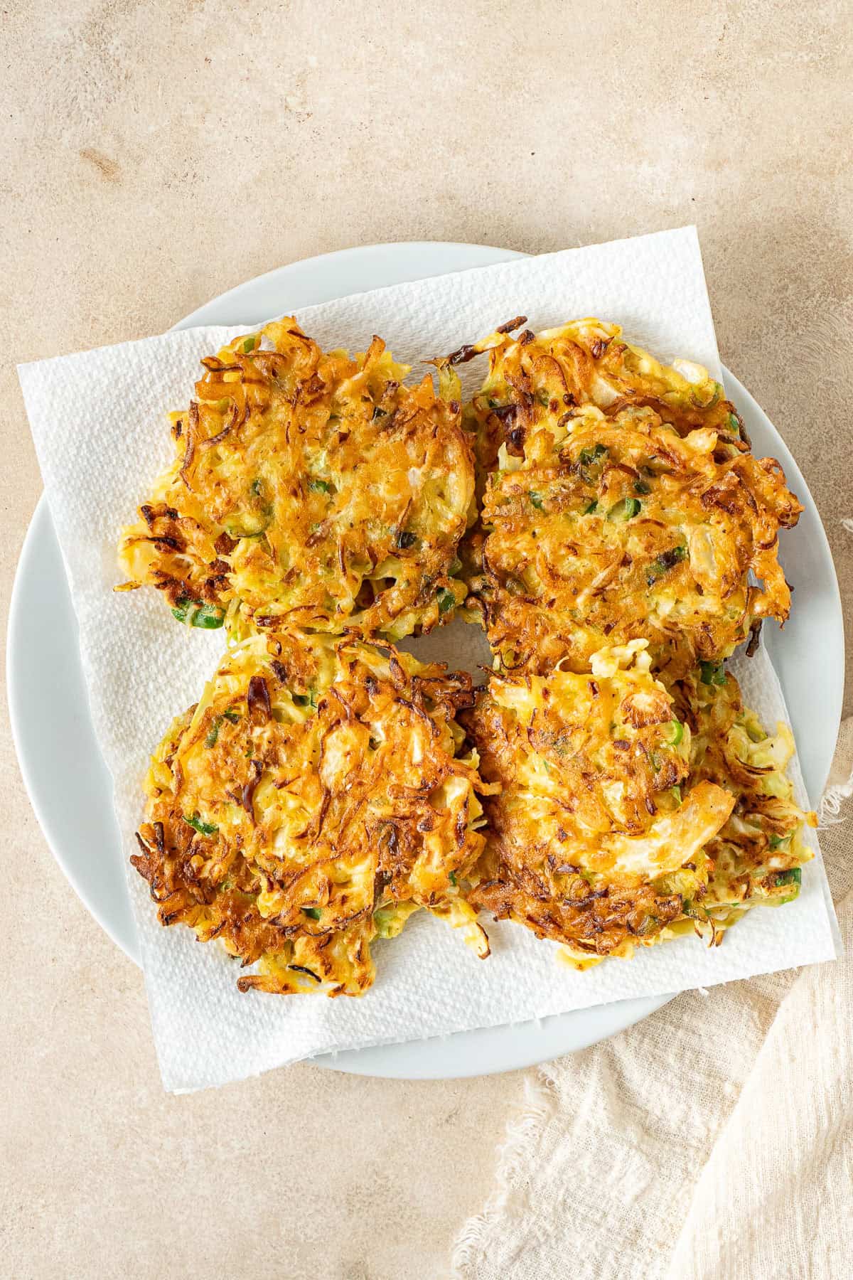 The coked cabbage fritters on a plate lined with paper towel.