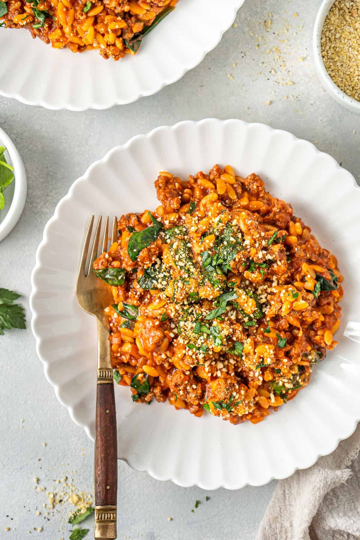 The creamy beef orzo served in a white bowl with a fork.