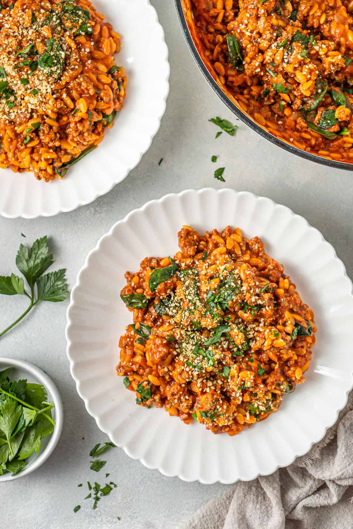 The creamy risoni and beef in while plates with parsley.