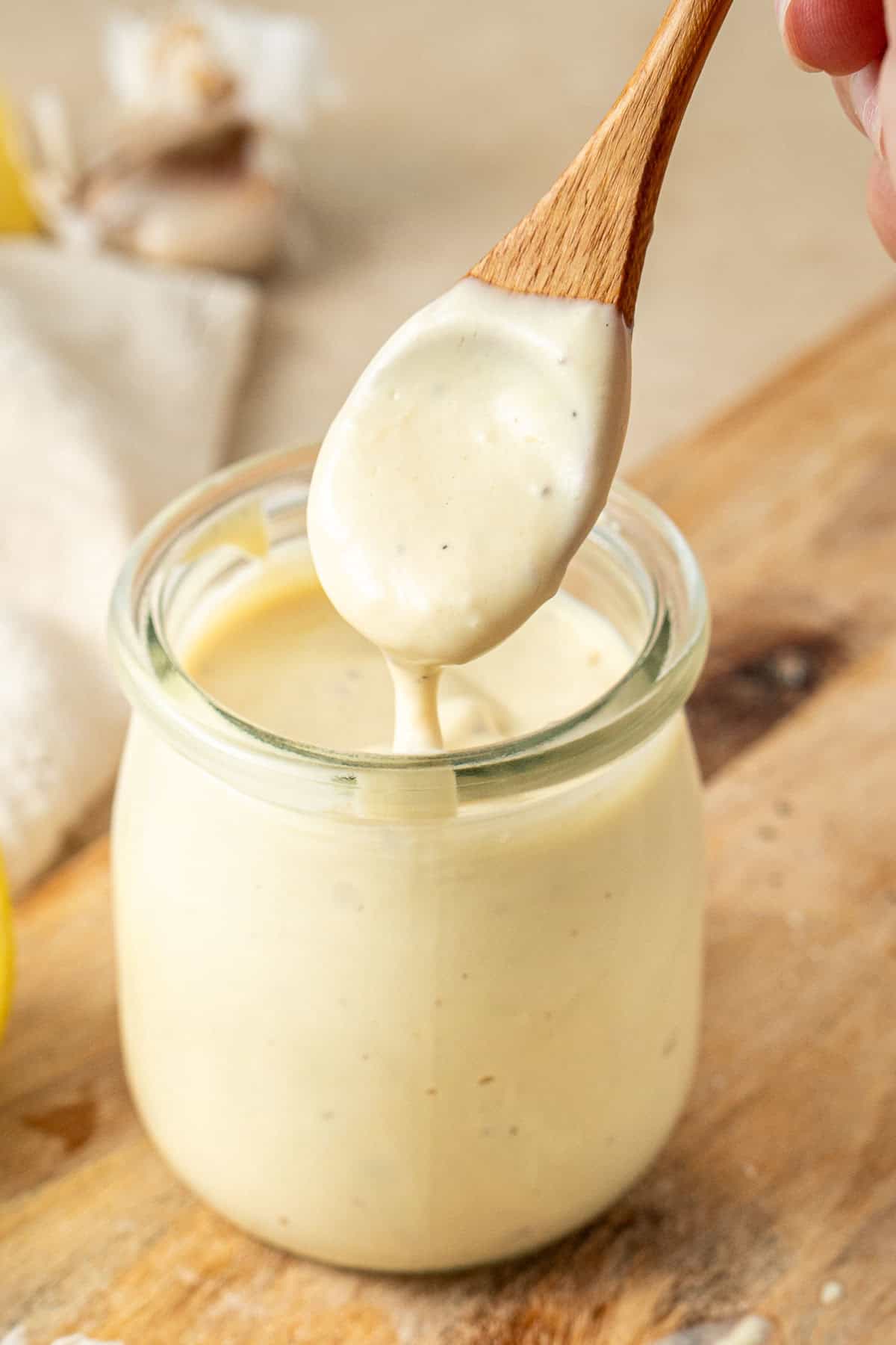 The dairy free caesar salad ingredients in a small jar with a spoon.