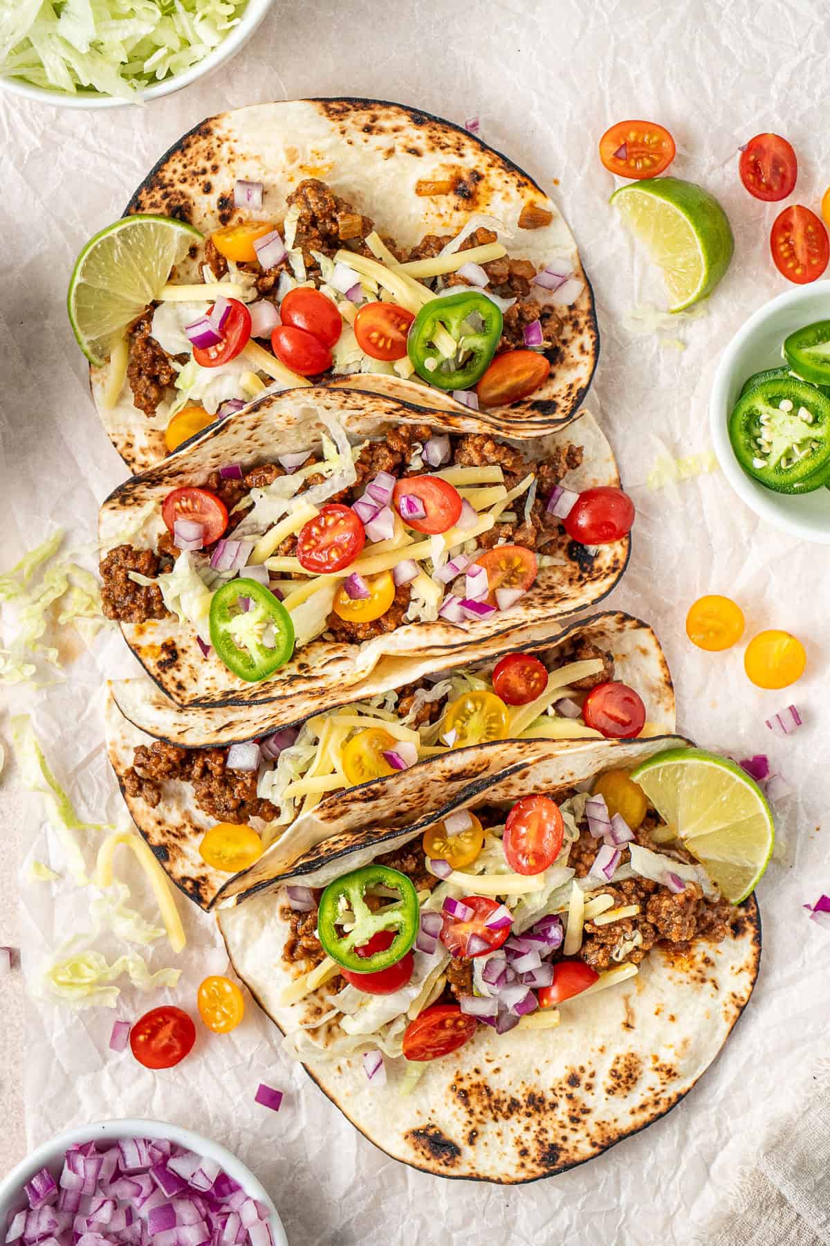 Ground beef tacos with cheese, tomato and onion.