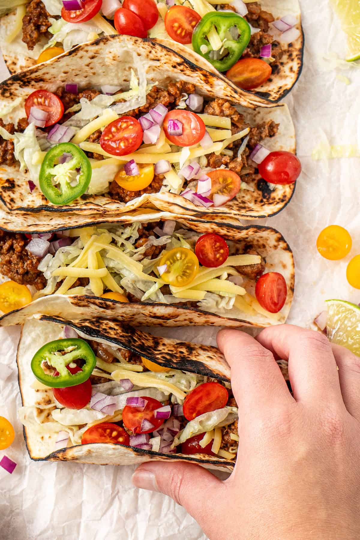A hand picking up a ground beef taco. 