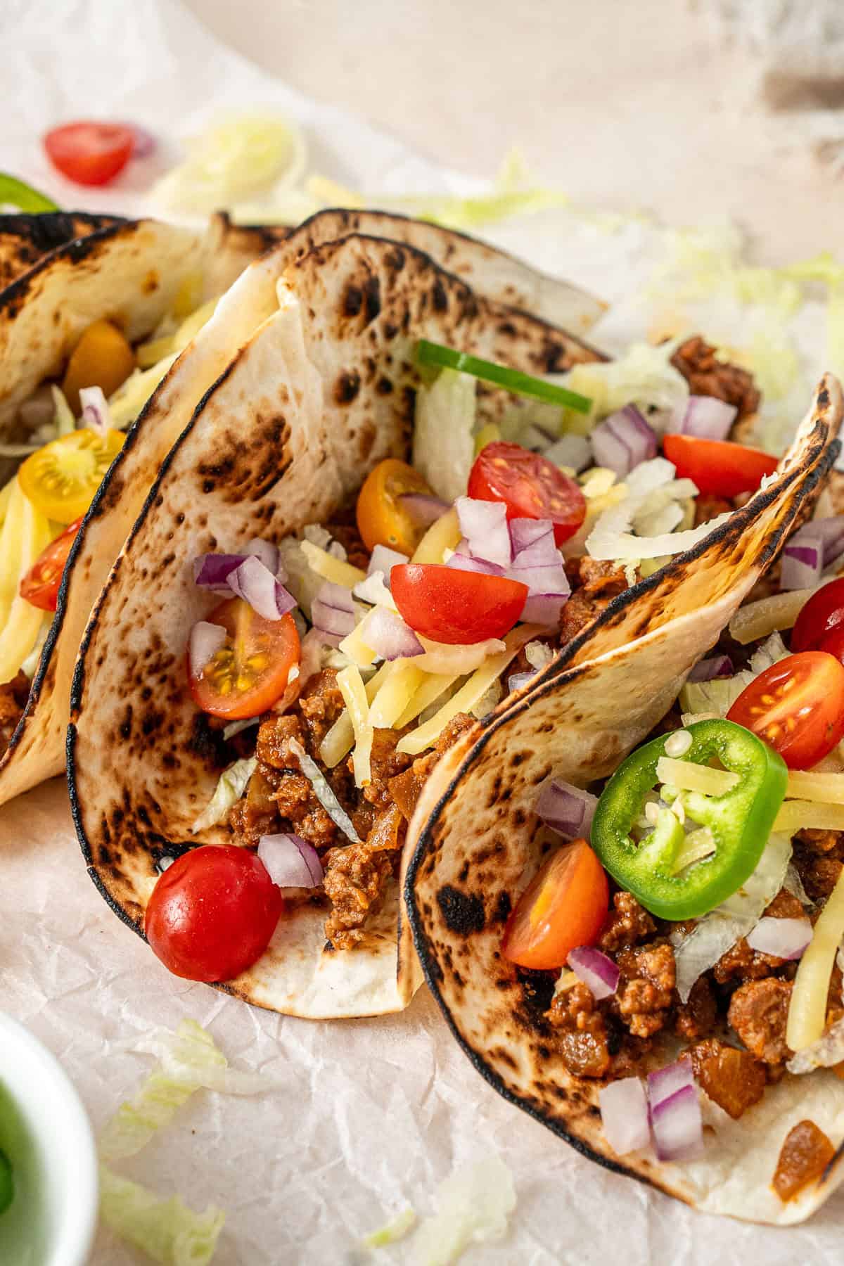 Close up on a beef mince taco with tomato, cheese and onions.