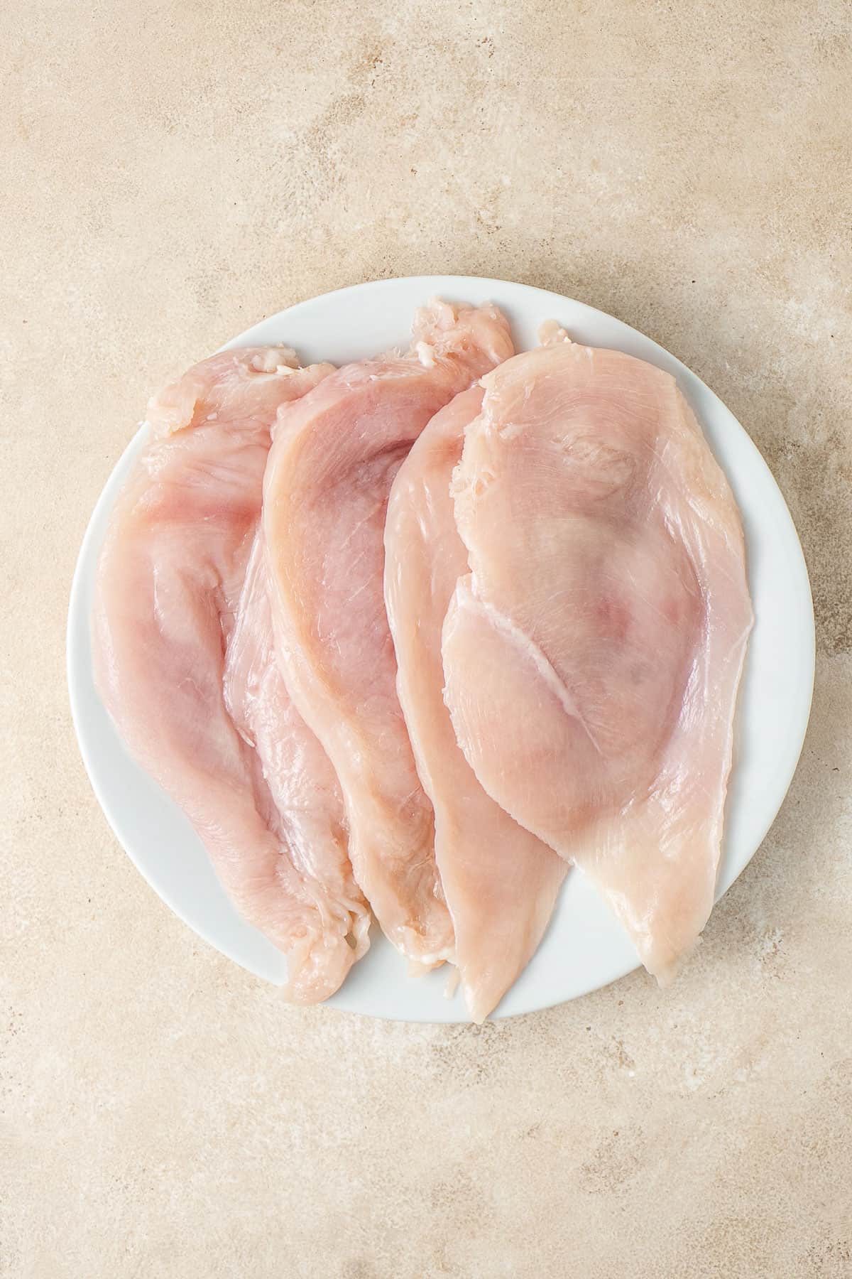 Chicken breast cut in half and laid on a white plate.