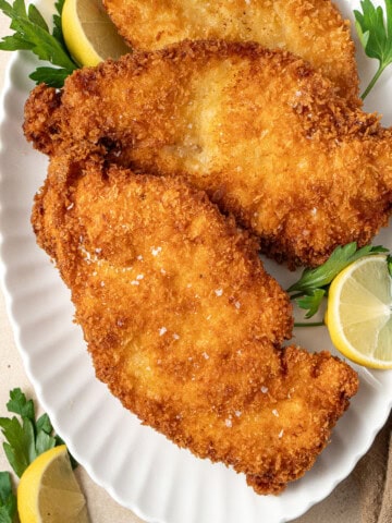 Chicken schnitzels on a white plate.