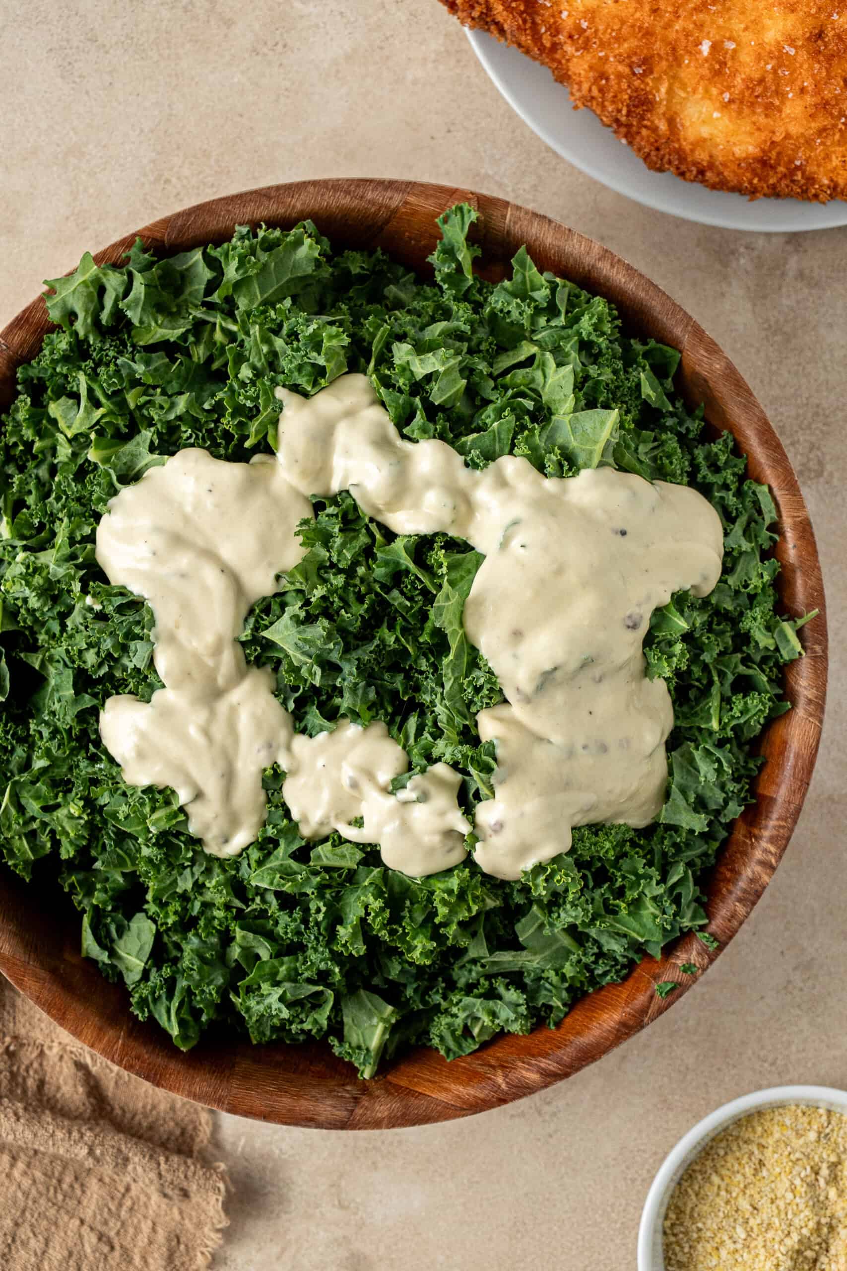 chopped kale in a bowl with dairy free caesar salad dressing.