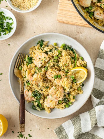 Lemon orzo with prawns served in a bowl with a fork.