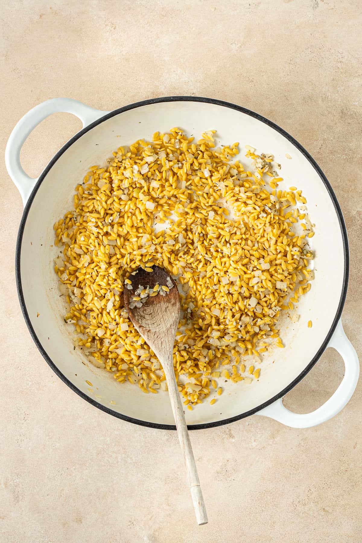 Toasting the orzo in the pan with a wooden spoon.