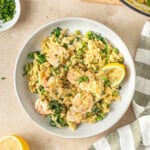 Lemon prawn orzo in a bowl with fresh lemon and parsley.