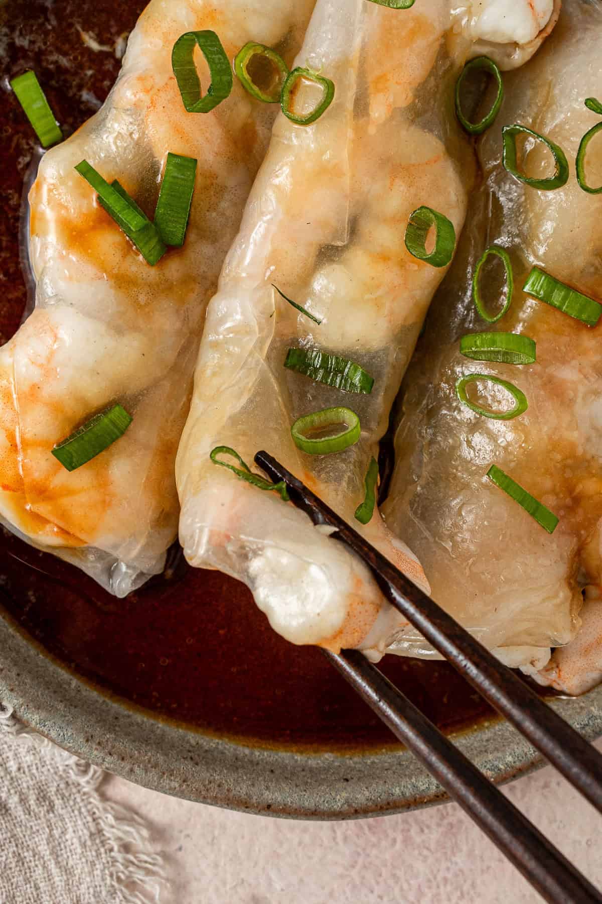 Close up of chopsticks picking up the steamed prawn roll. 