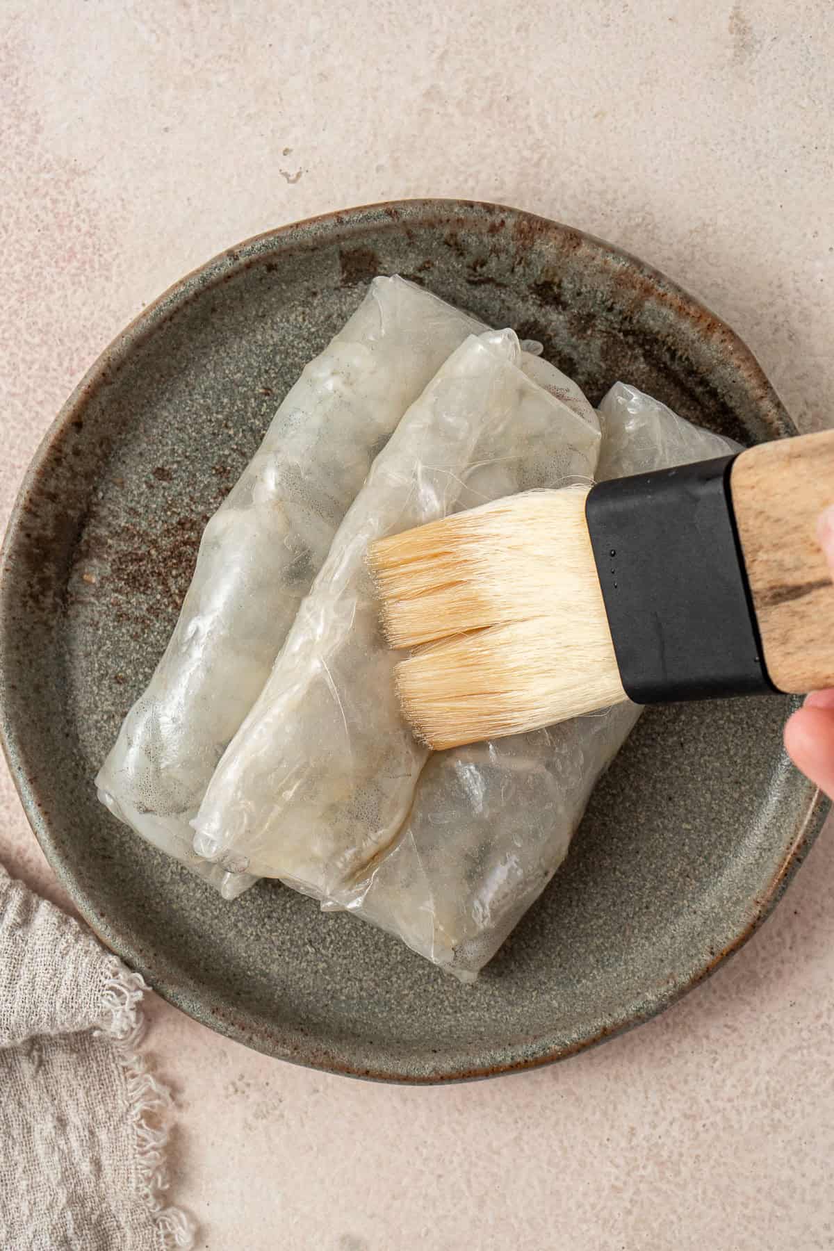 Brushing the rolls with sesame oil.
