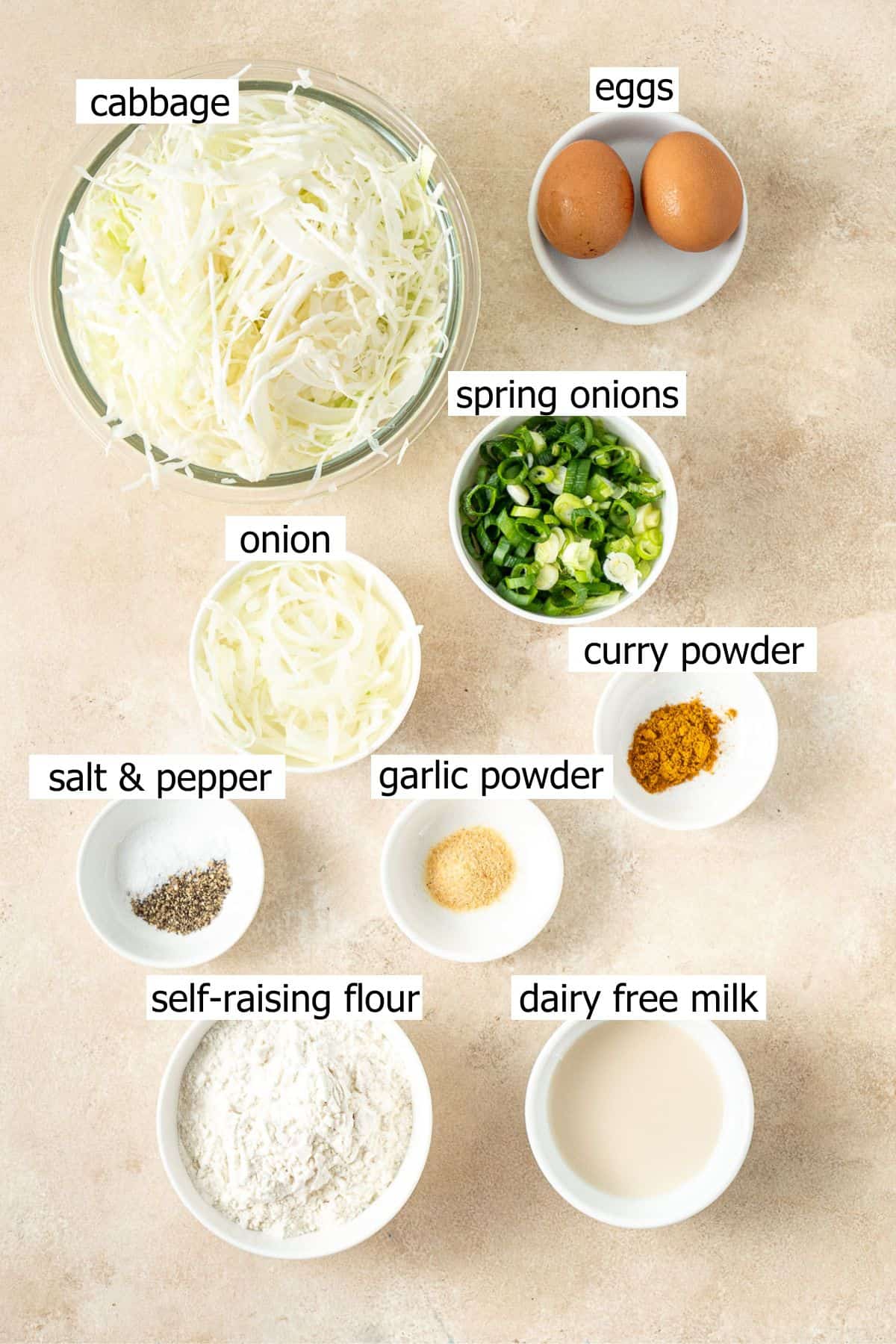 All ingredients needed to make cabbage fritters laid out in small bowls.