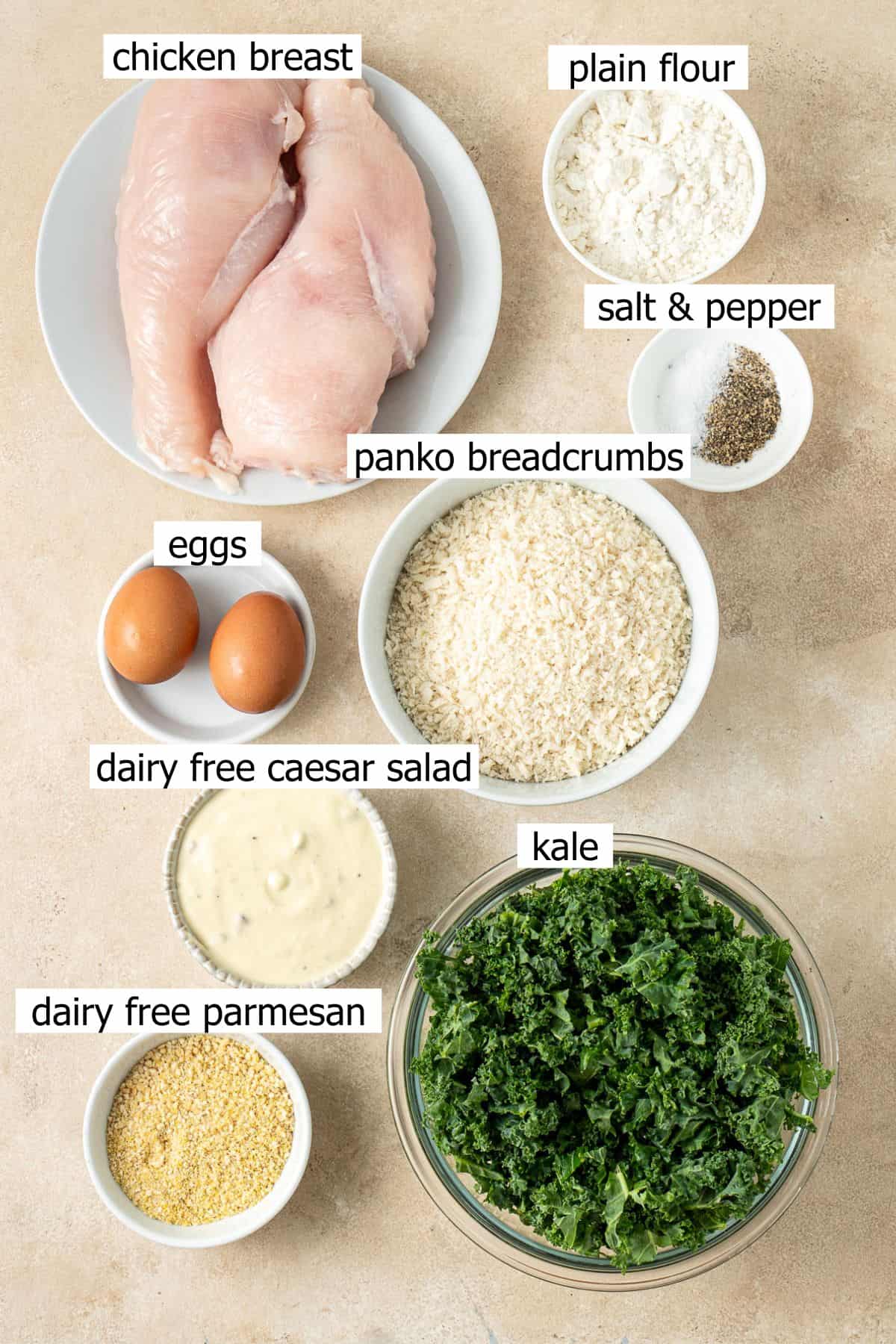 Kale caesar salad ingredients laid out in bowls.