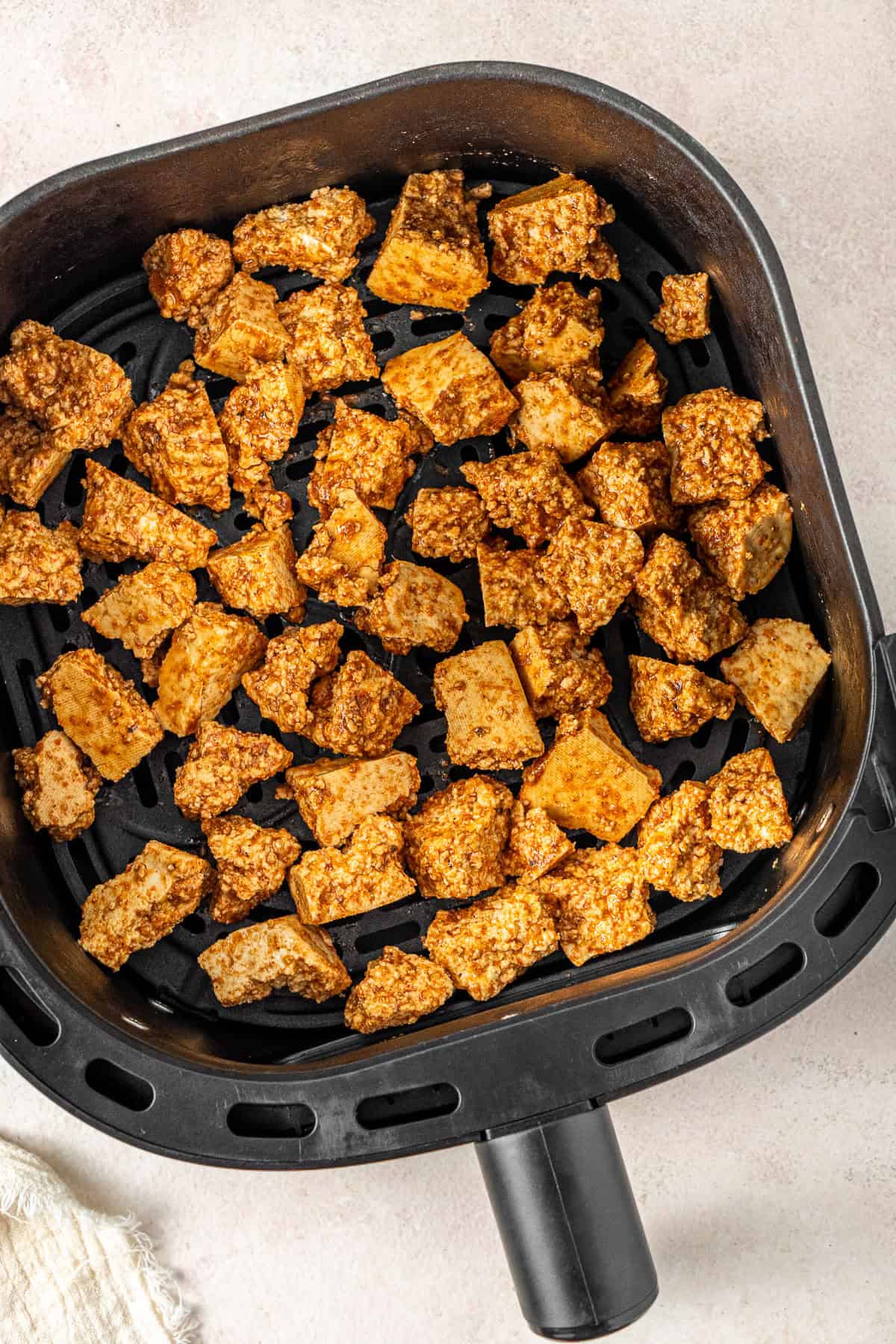 The tofu in a single layer in the air fryer basket.